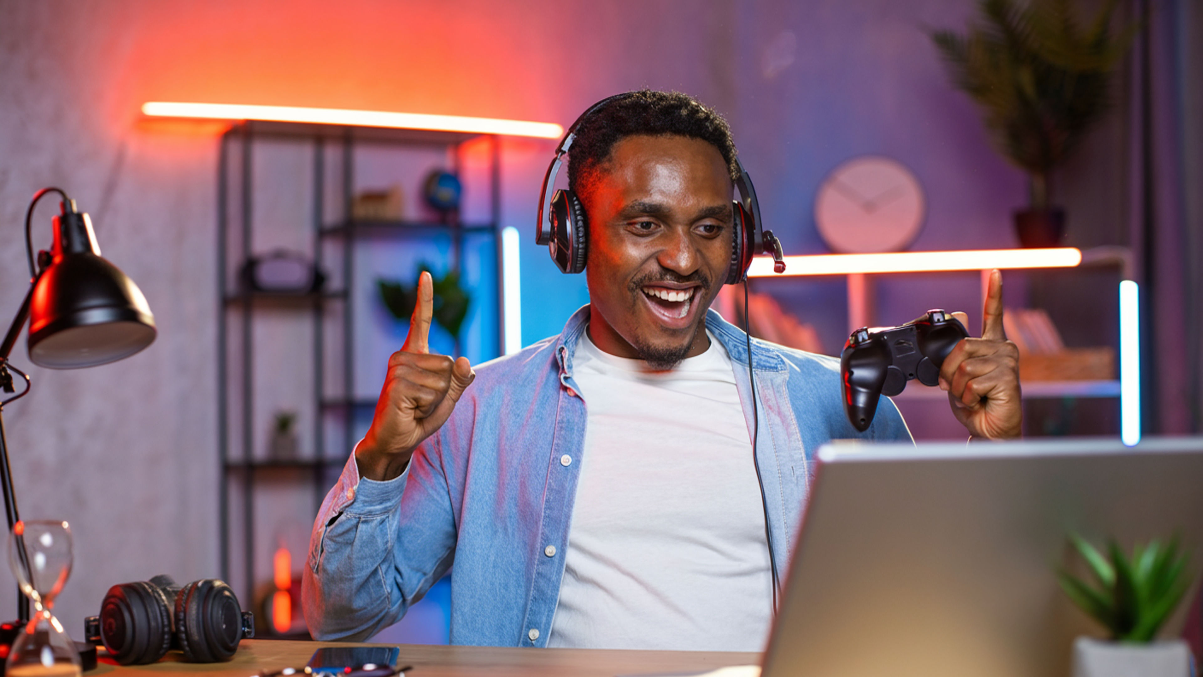 Emotional black man in headset playing games on laptop.