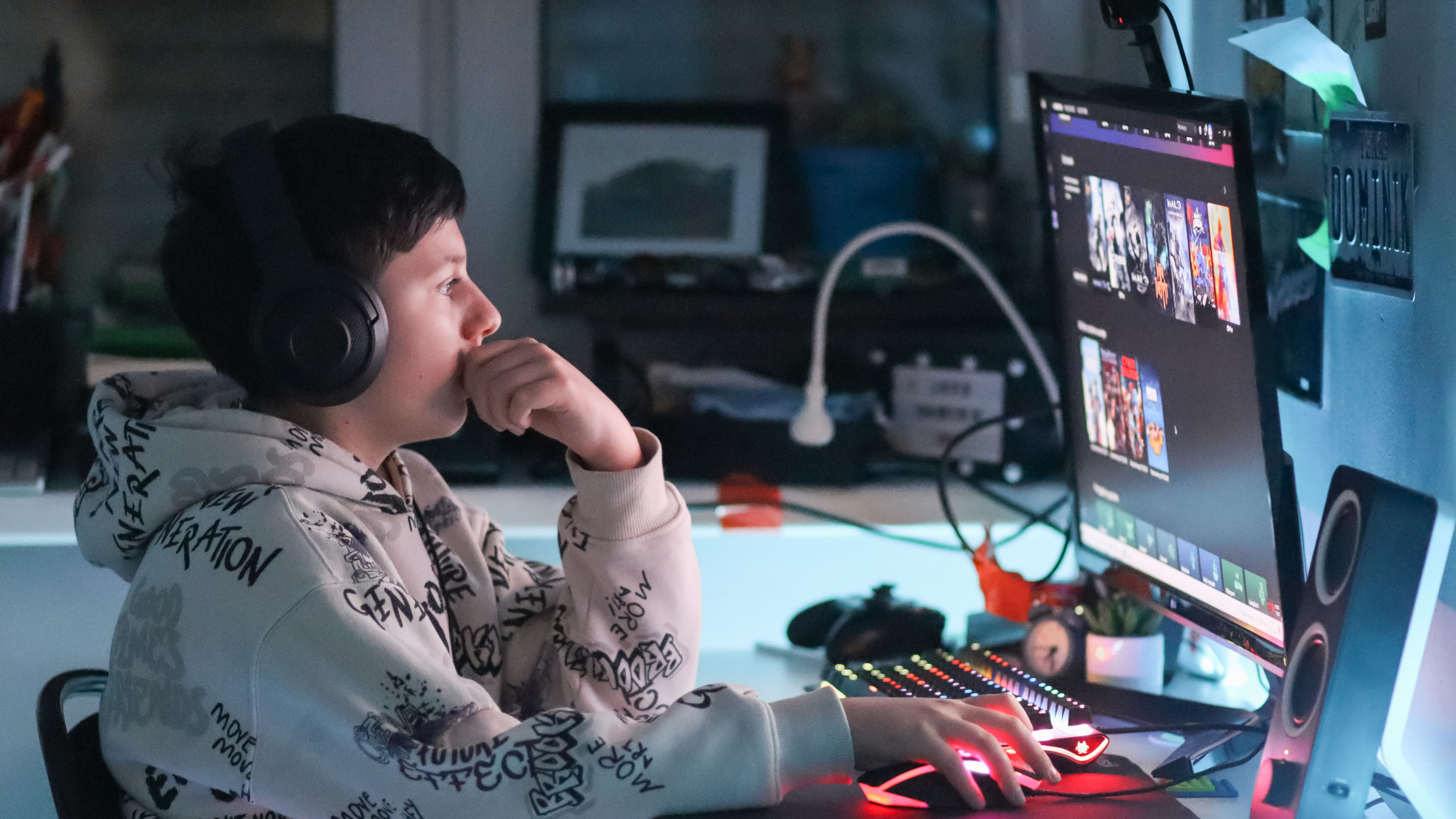 A teenage gamer playing on a computer, surrounded by gaming essentials and apparel.