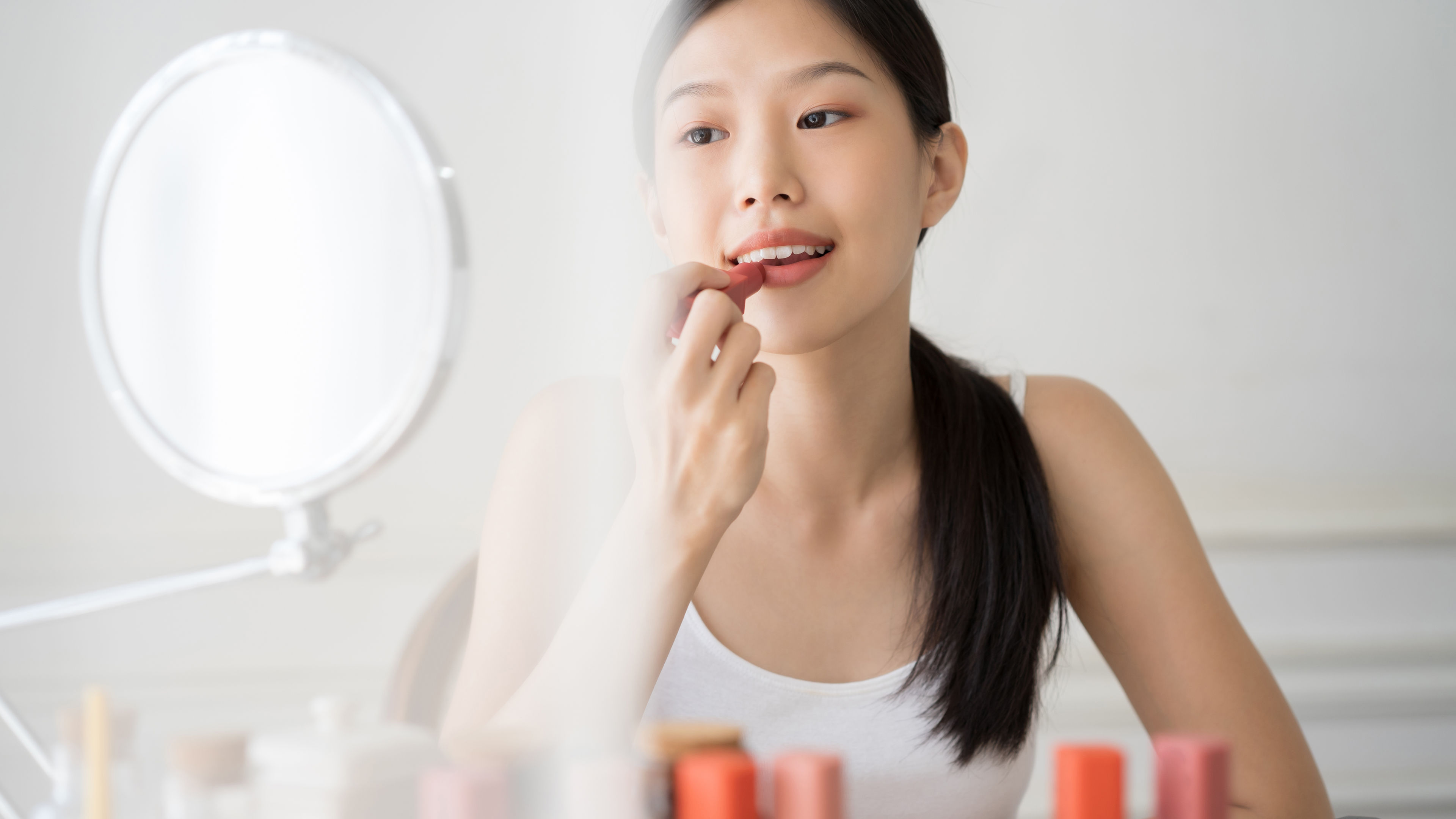 Young Asian girl is using lipstics