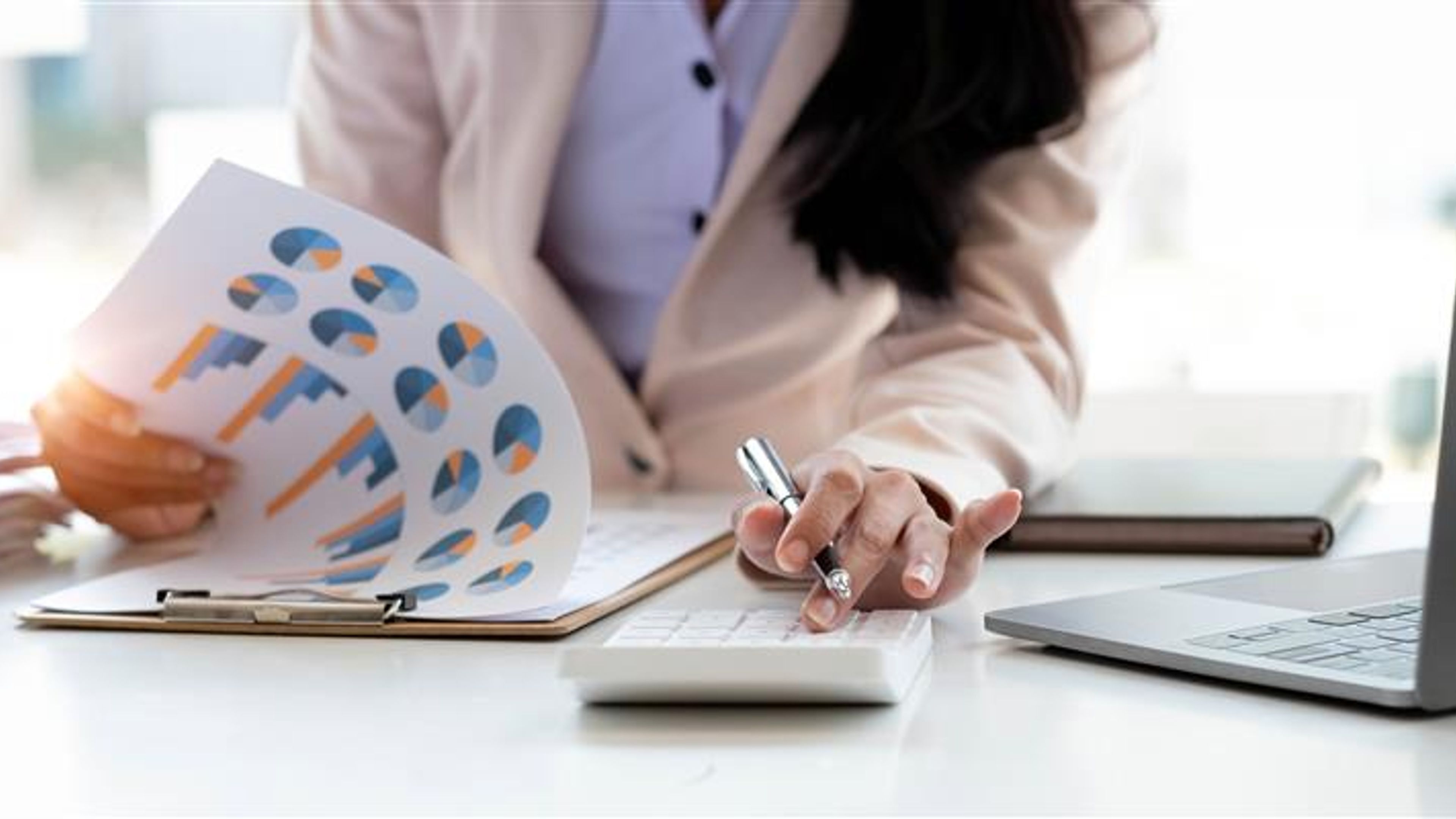 Close up Business woman using calculator and laptop for do math finance on wooden desk in office and business working background, tax, accounting, statistics and analytic research concept. 