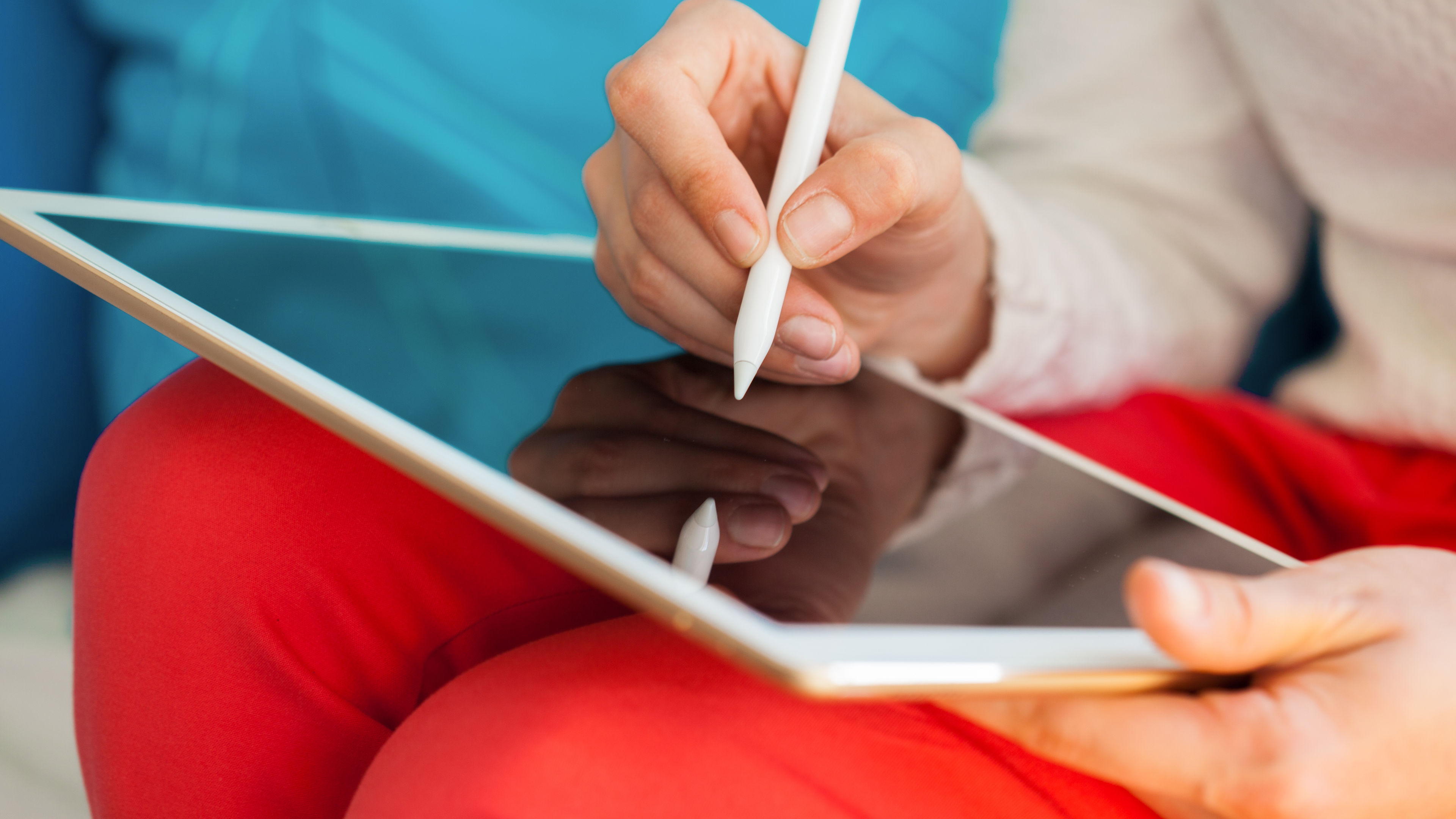 Person writing on a digital tablet using a white stylus.