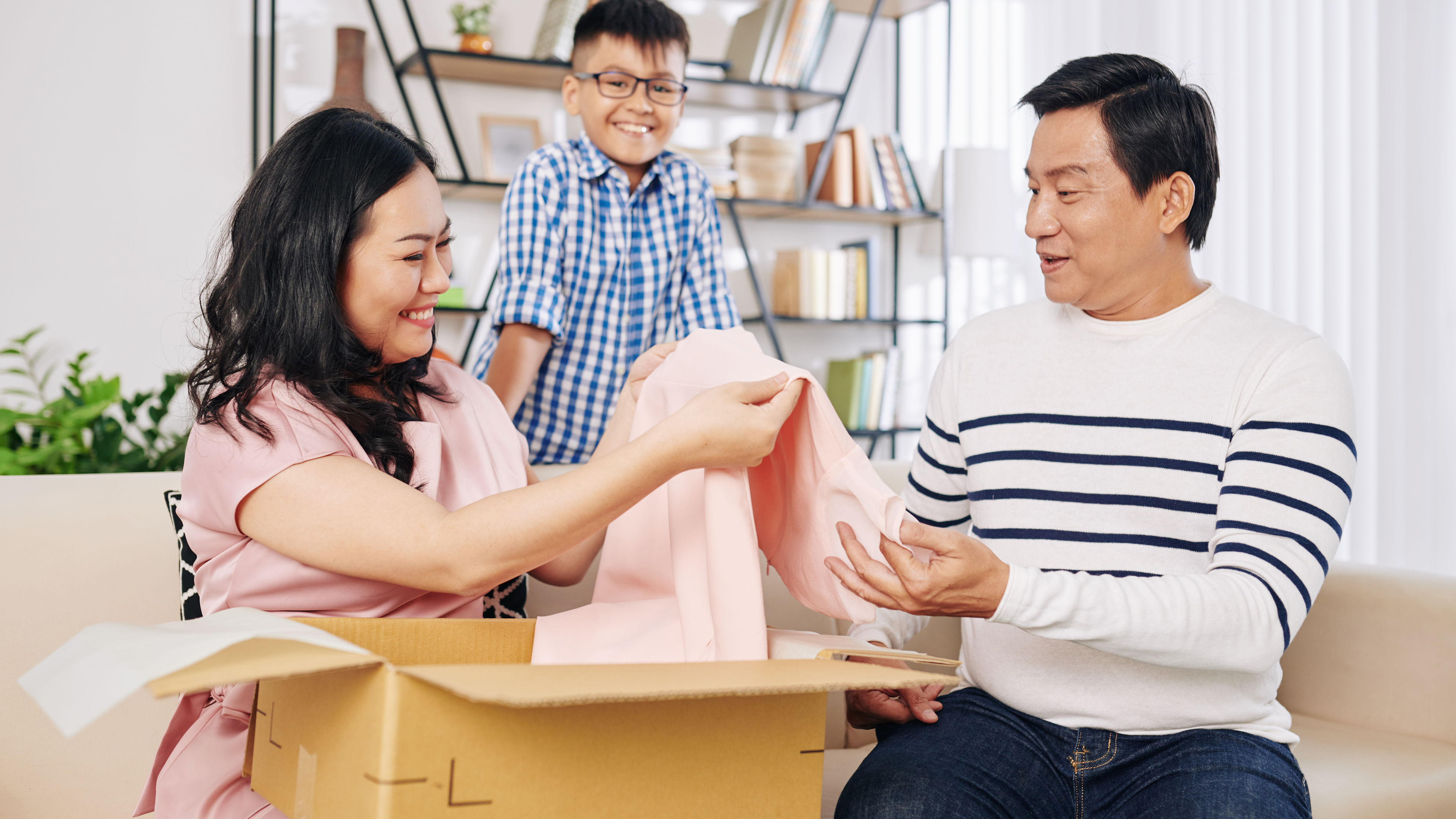 A family of three opening a gift box with a dress