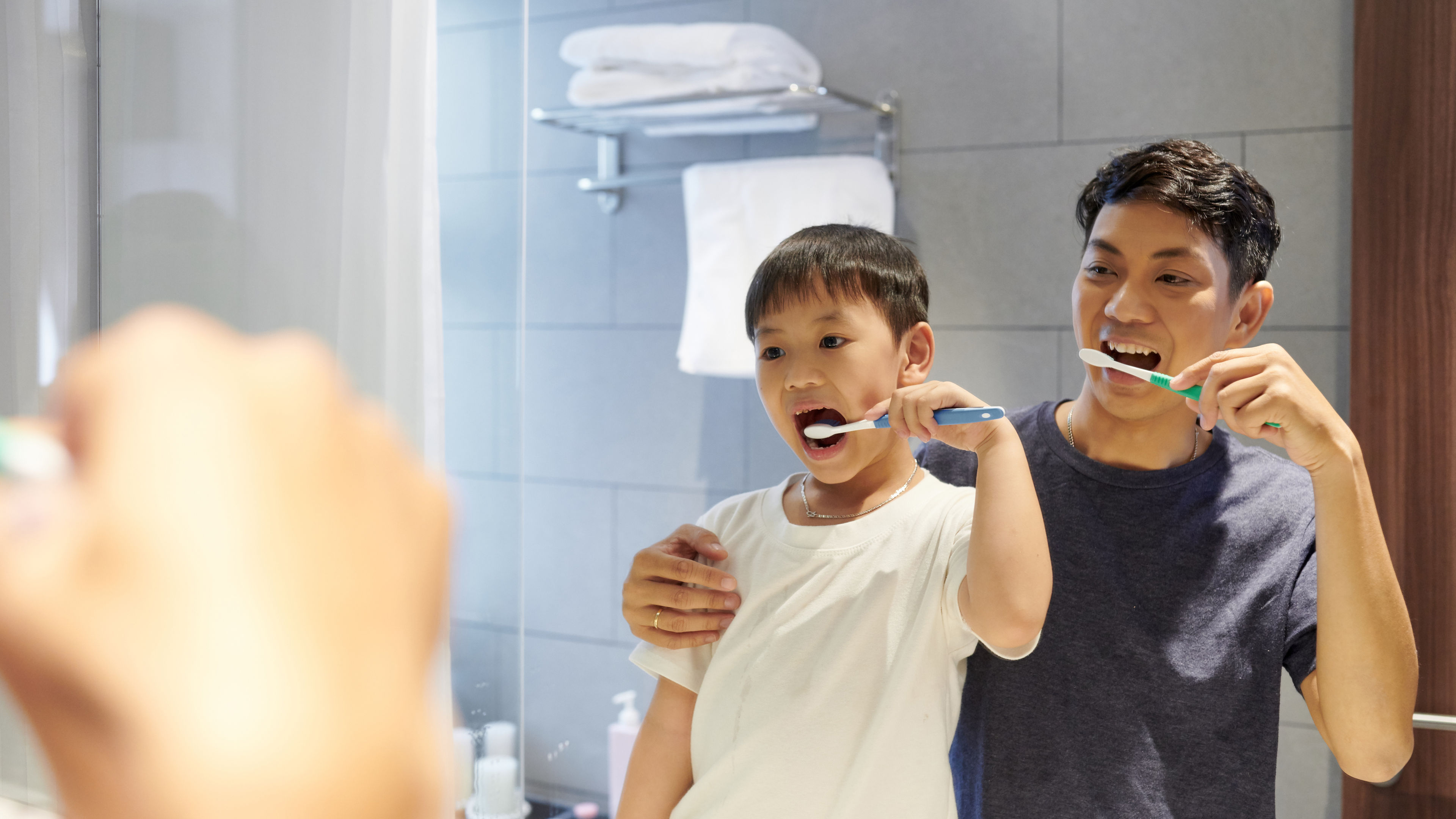 Boy brushing teeth with father