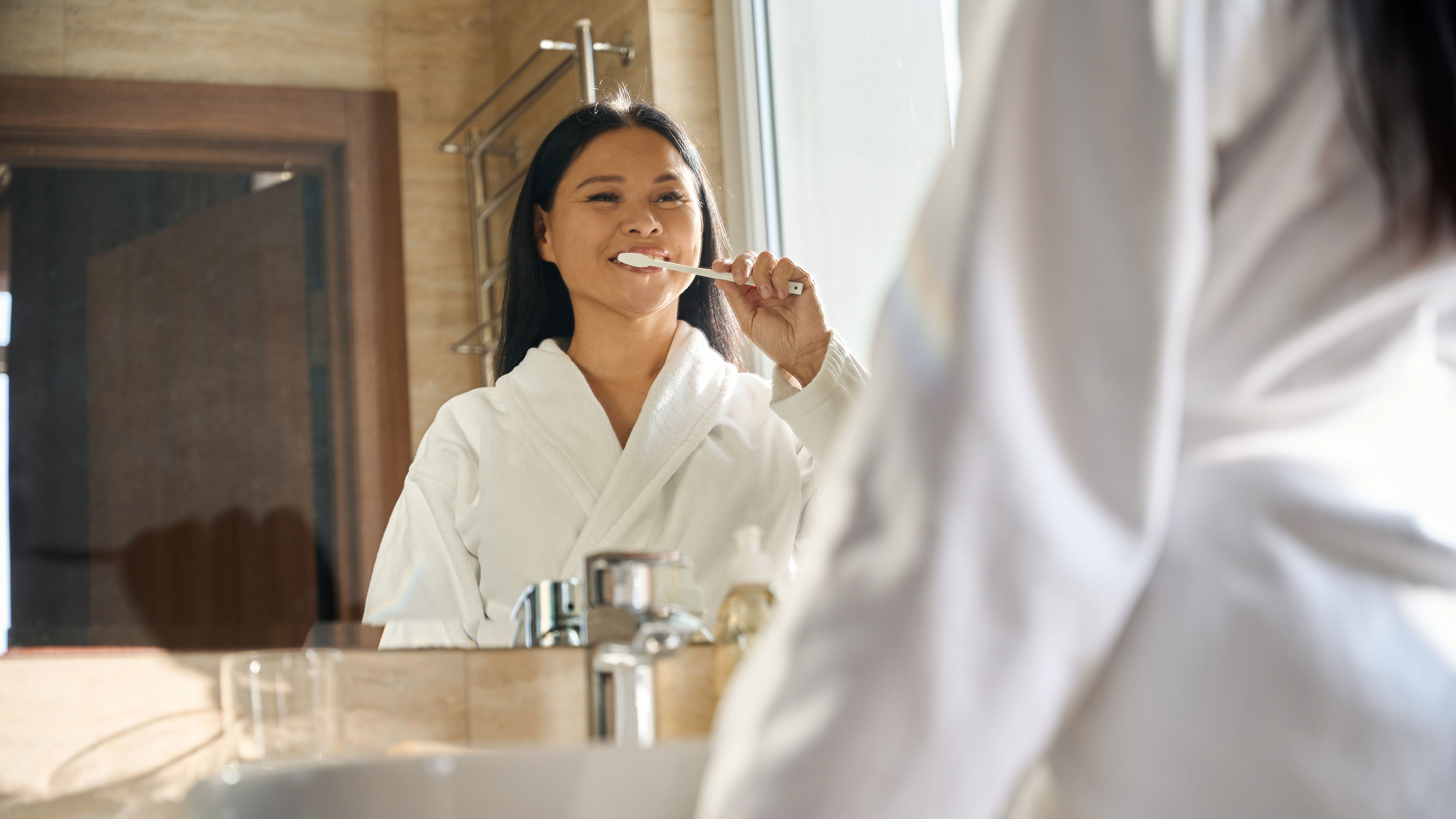 Cheerful woman enjoying tooth-brushing procedure in morning