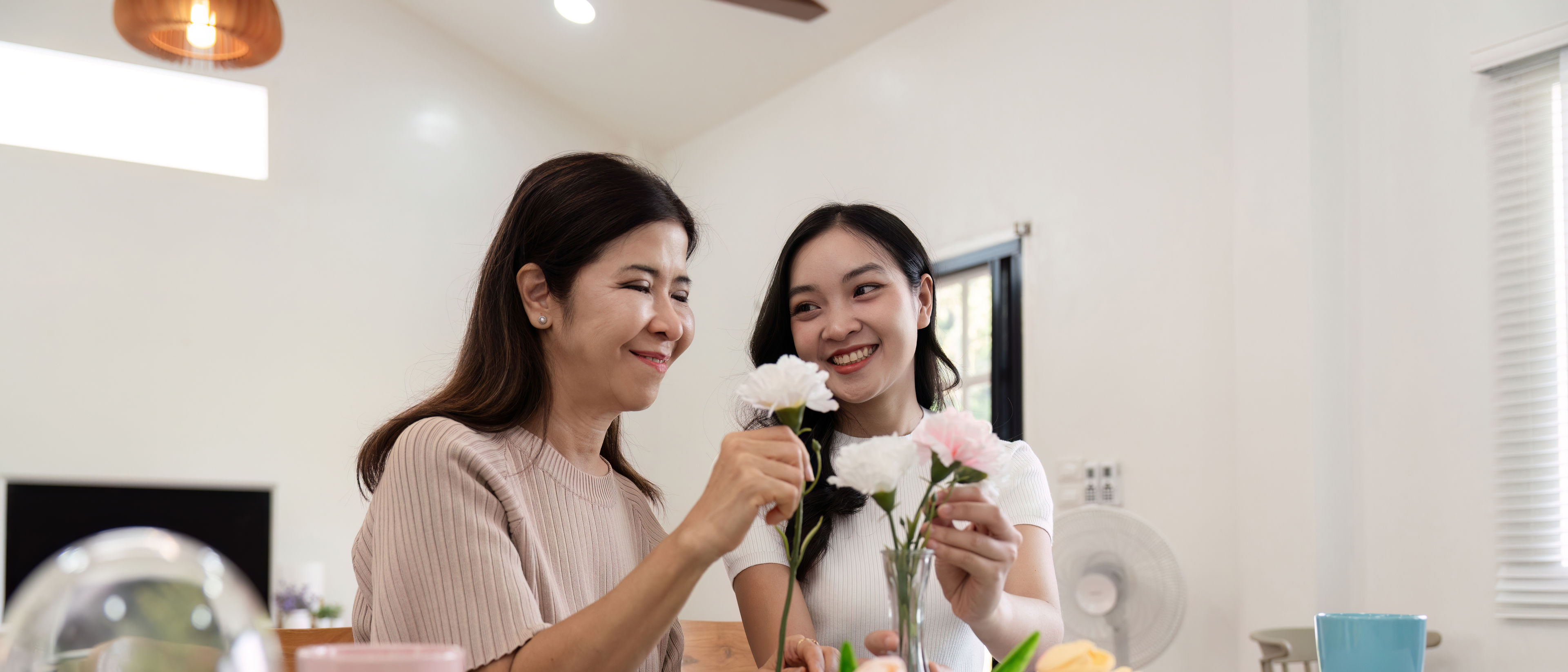 Mother and daughter arranging flower in vase