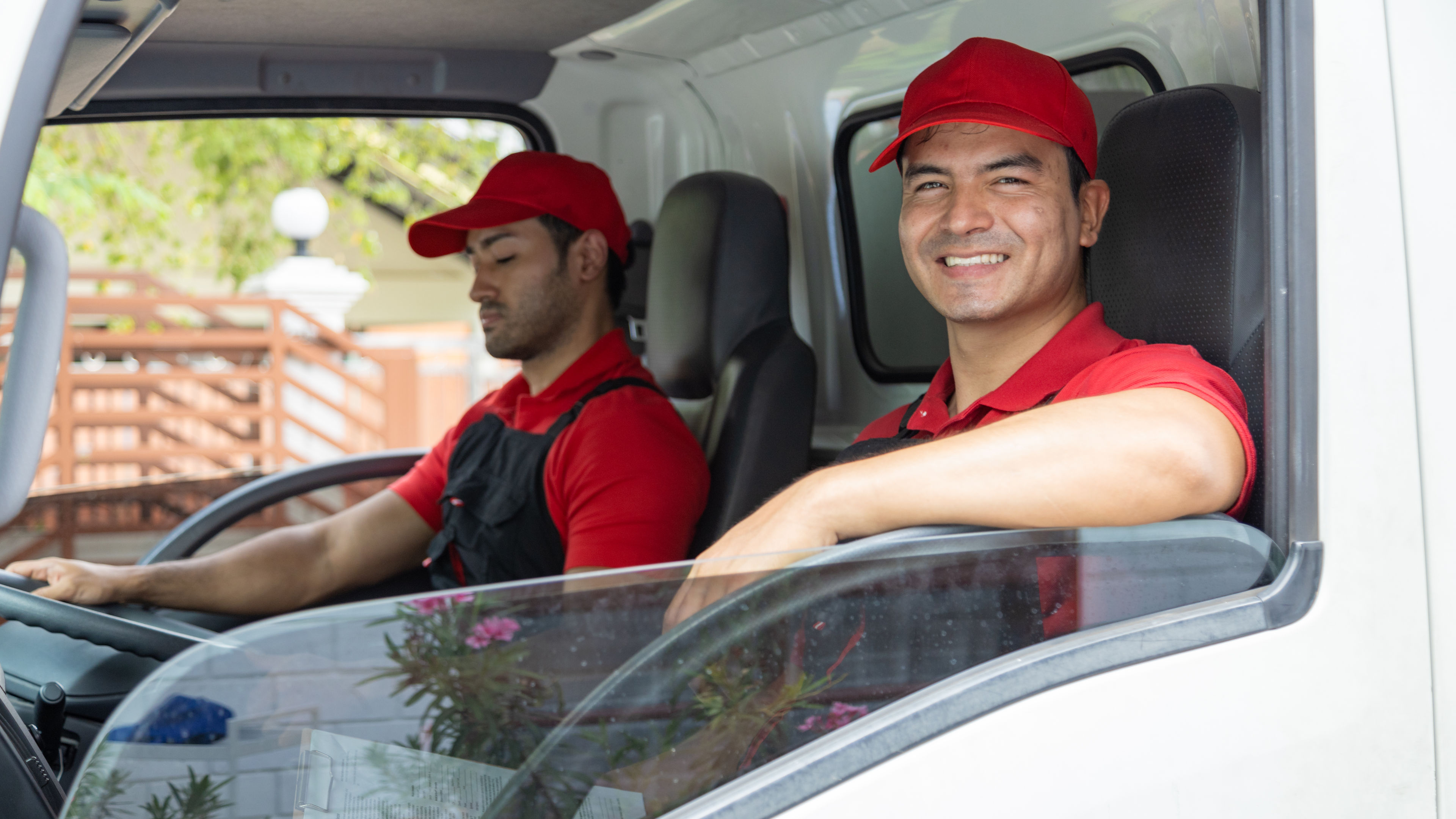 Two happy delivery men sitting in a van during their working time