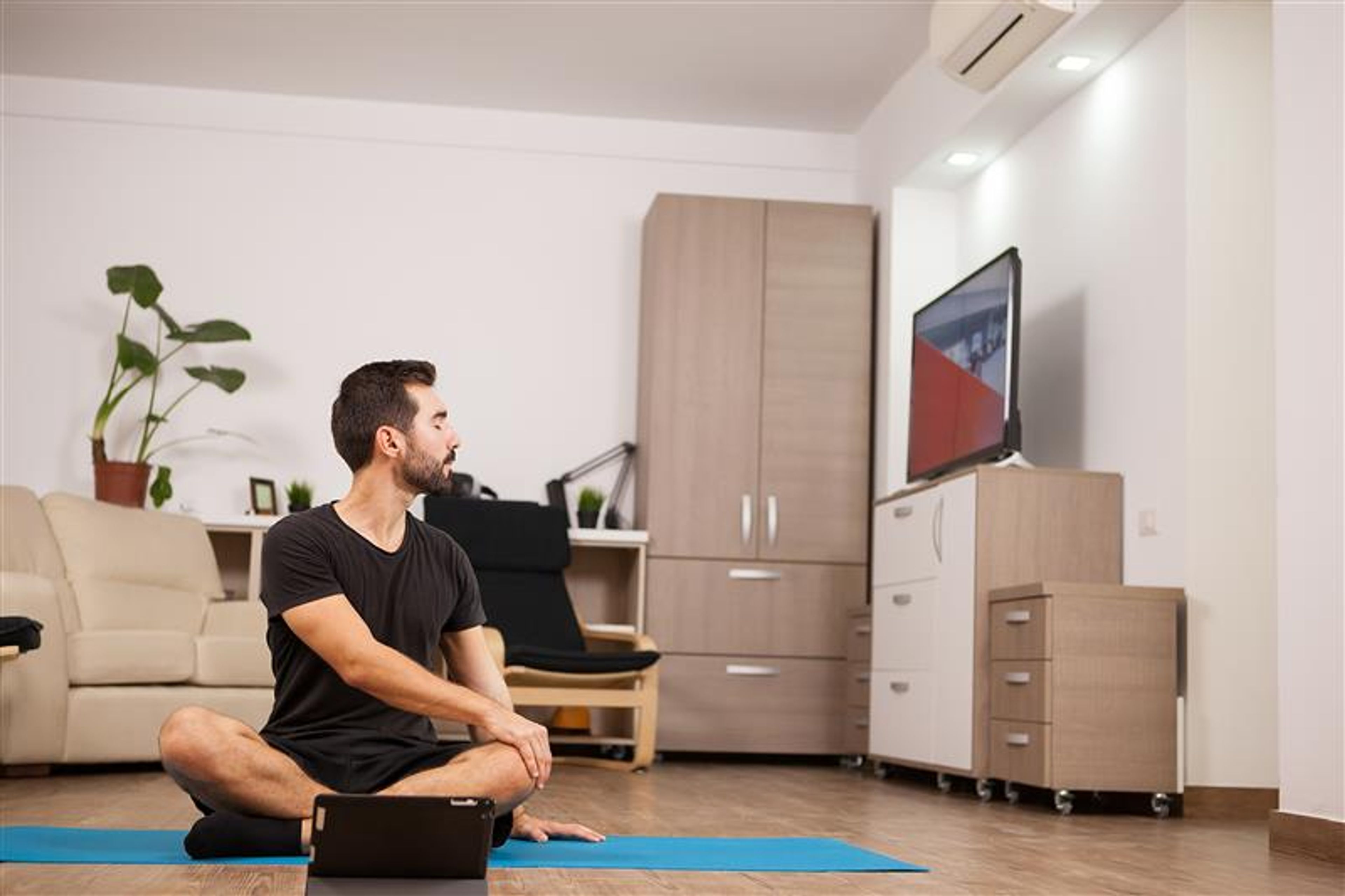 A man doing yoga with the help of tv 