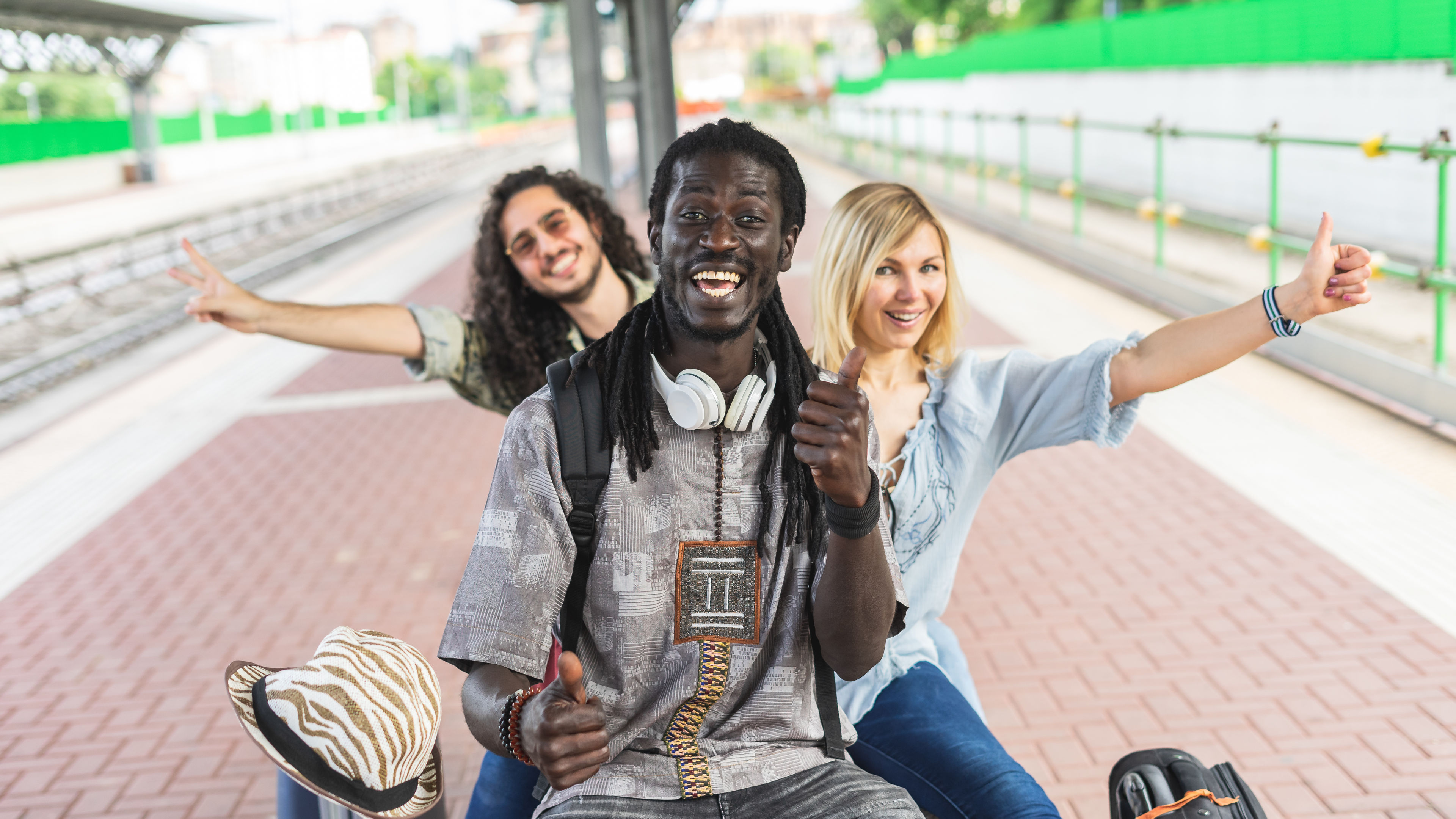 Group of multiracial friends waiting train at station rail