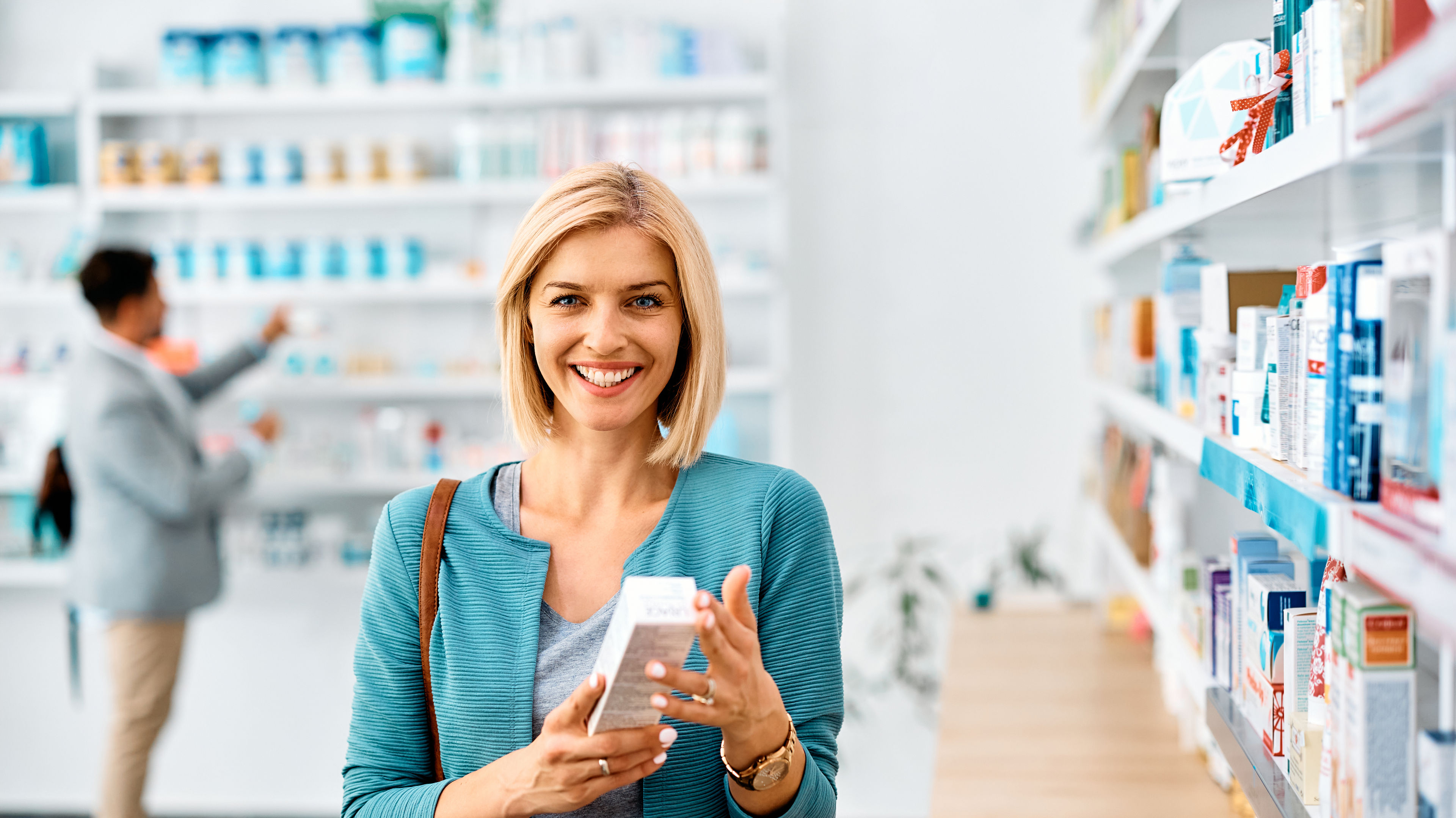 Happy woman in blue & grey outfit purchasing medical items from Pharmacy