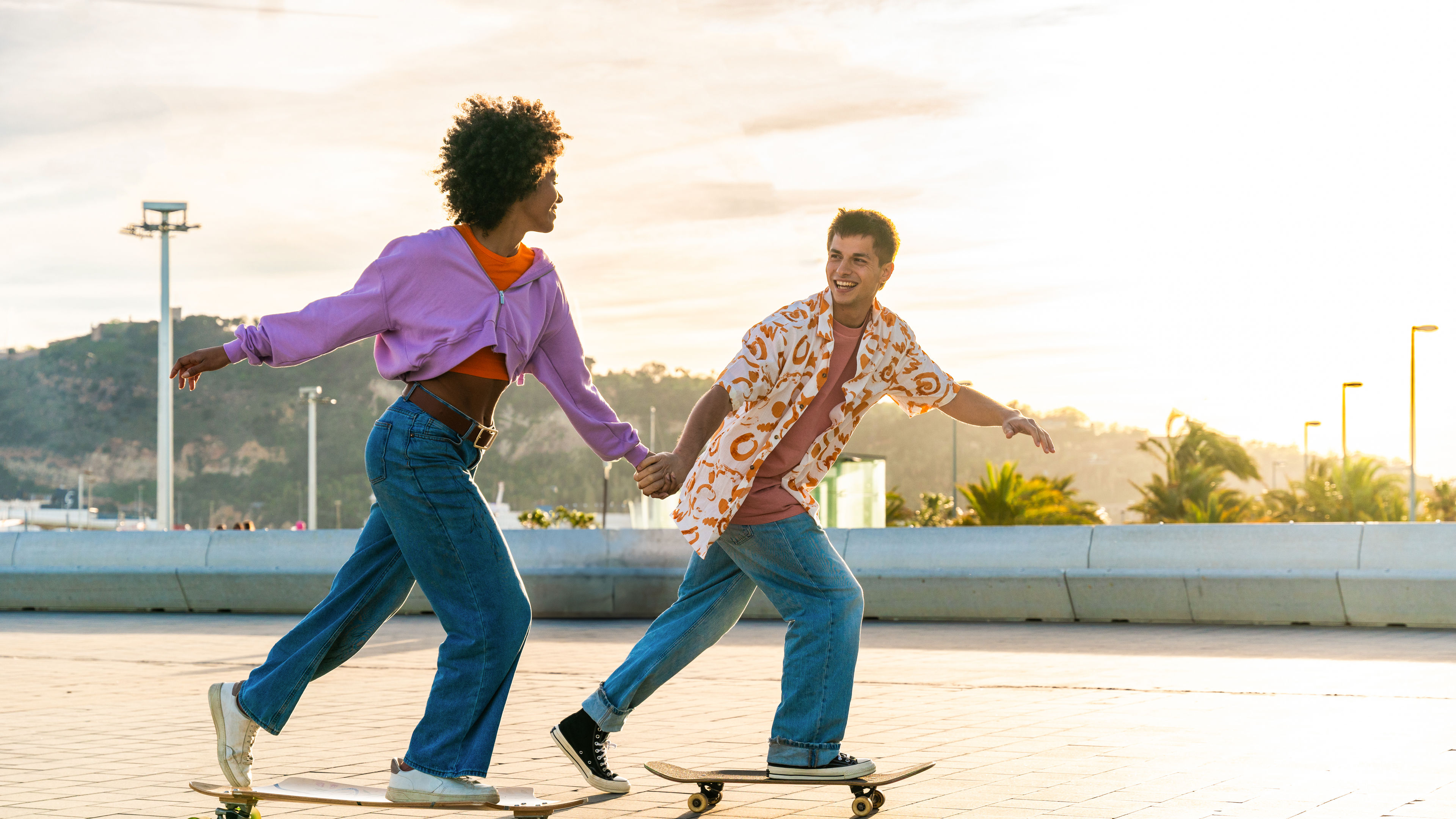 Young multiethnic modern couple dating outdoors with skating