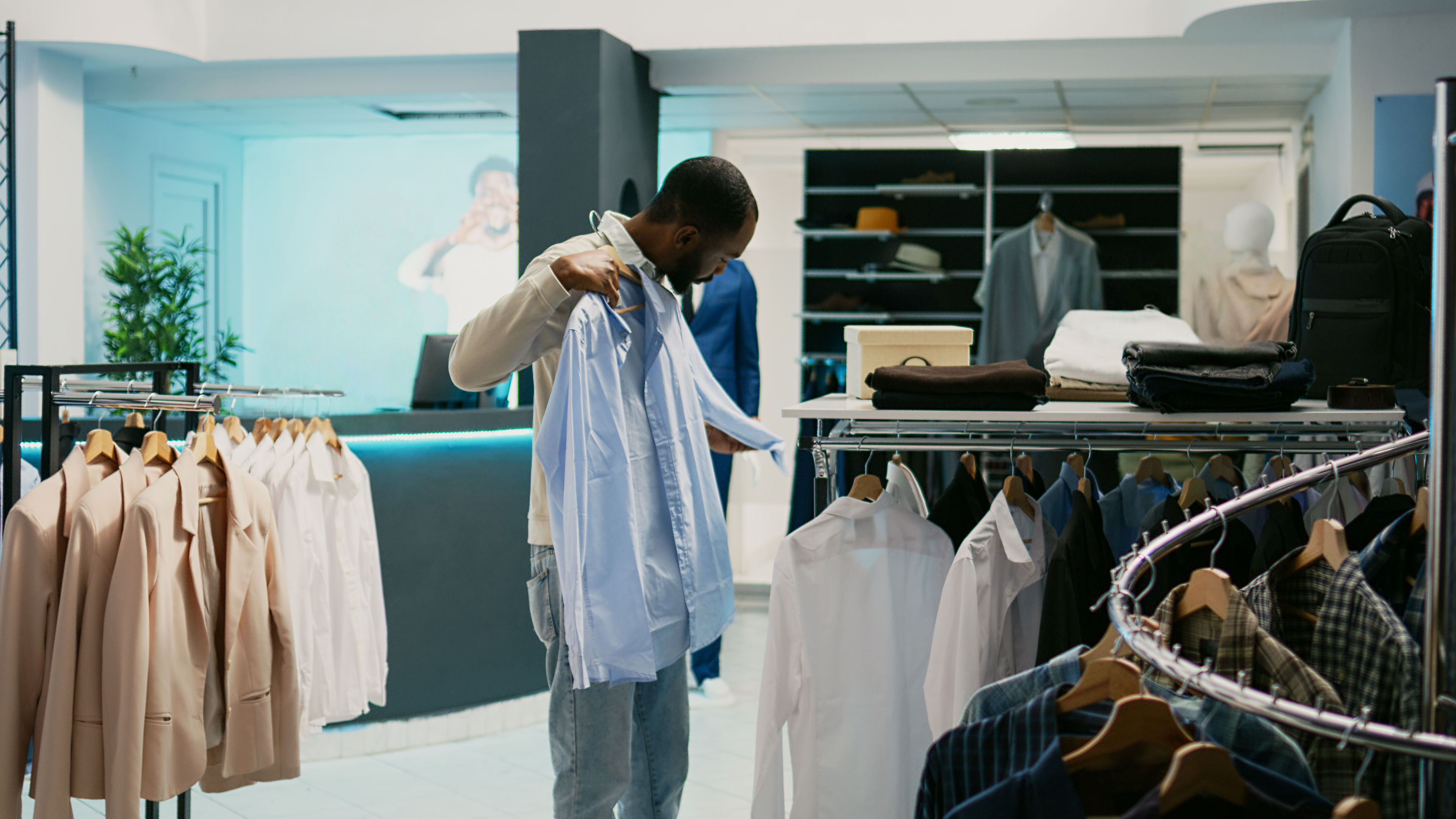 Man examining fabric of formal shirts in cloth store.
