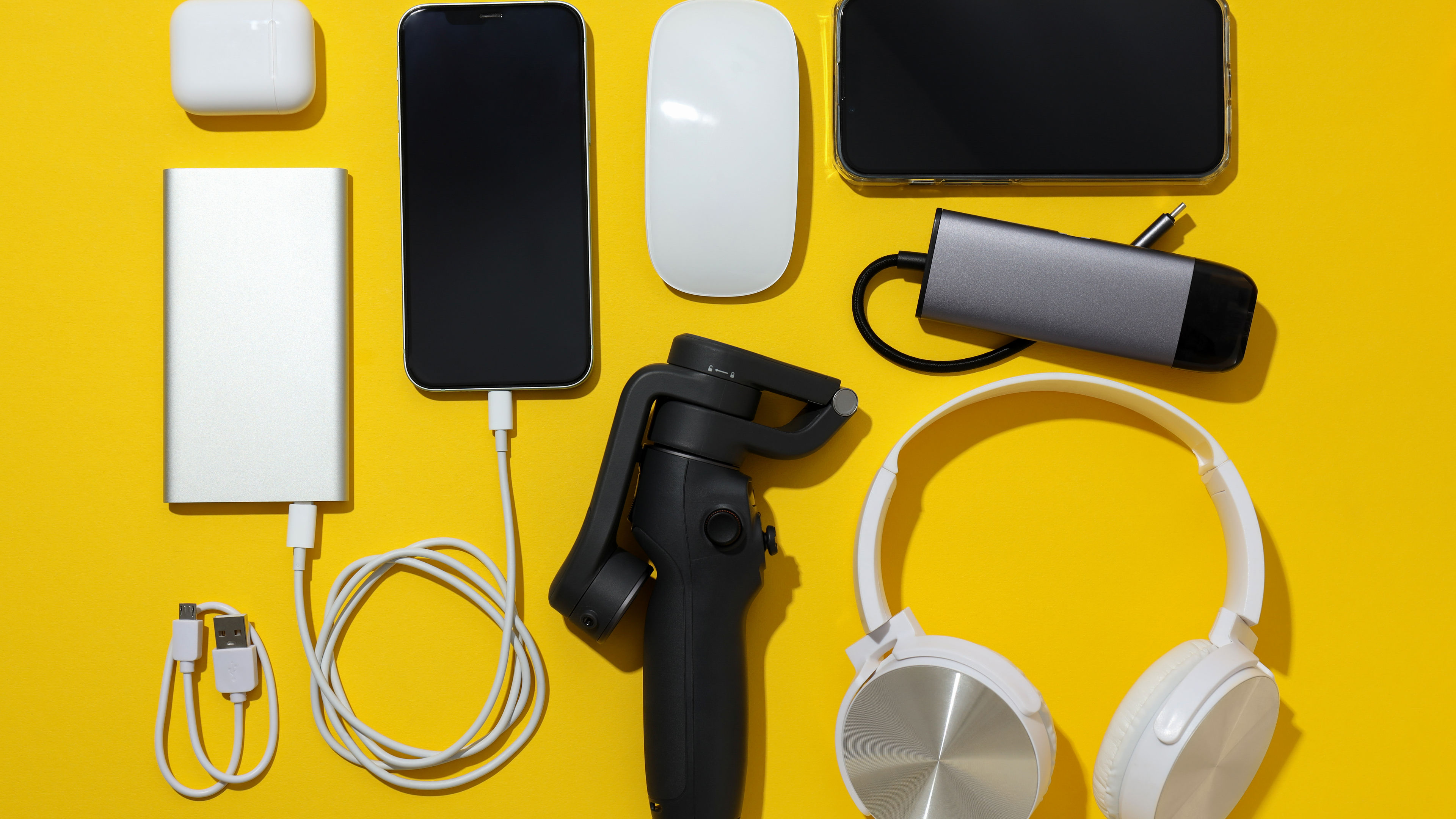 Two mobile phones, power bank and other gadgets arranged on a yellow background.