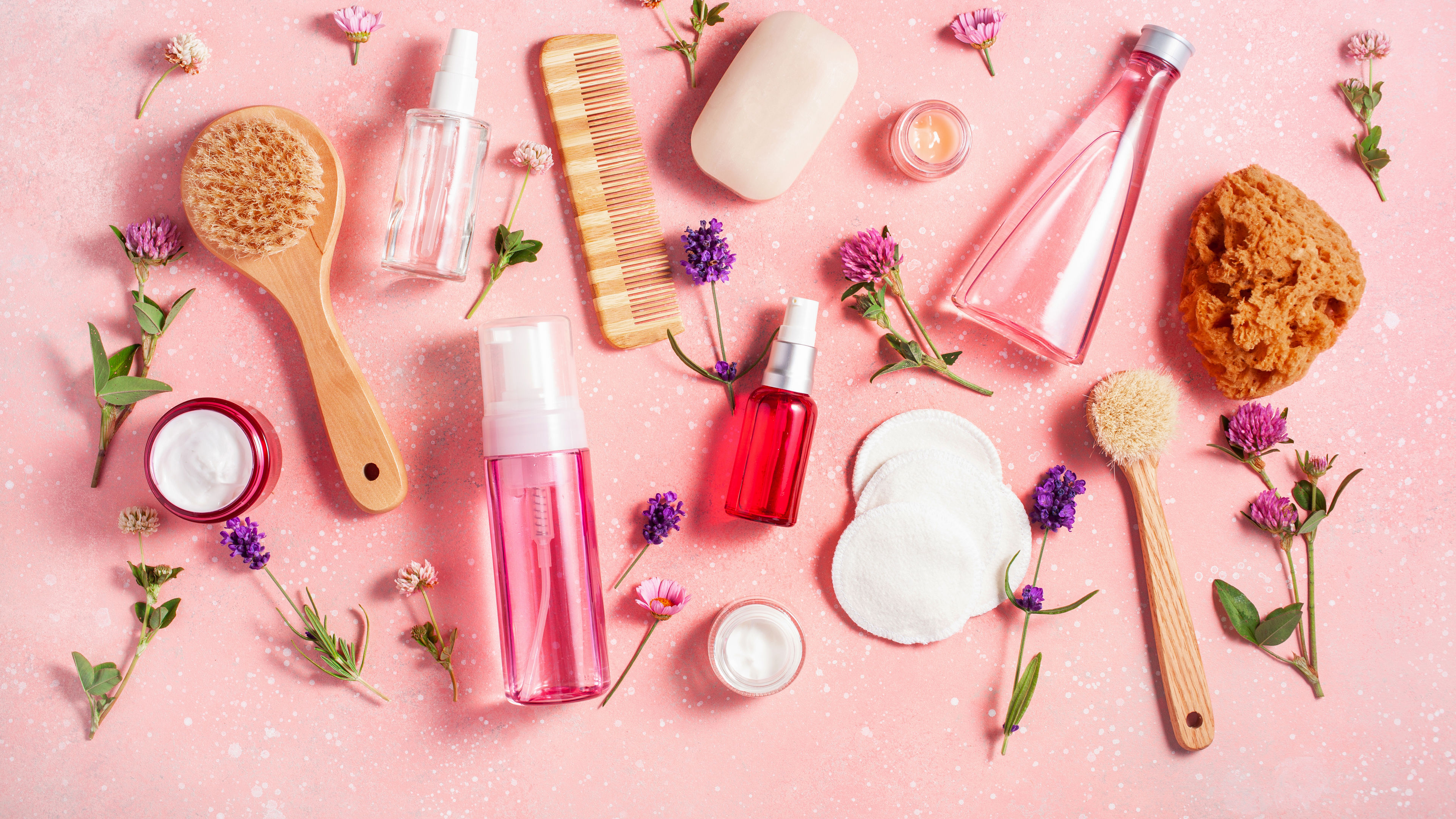Bath and body care products with wildflowers on a pink background.