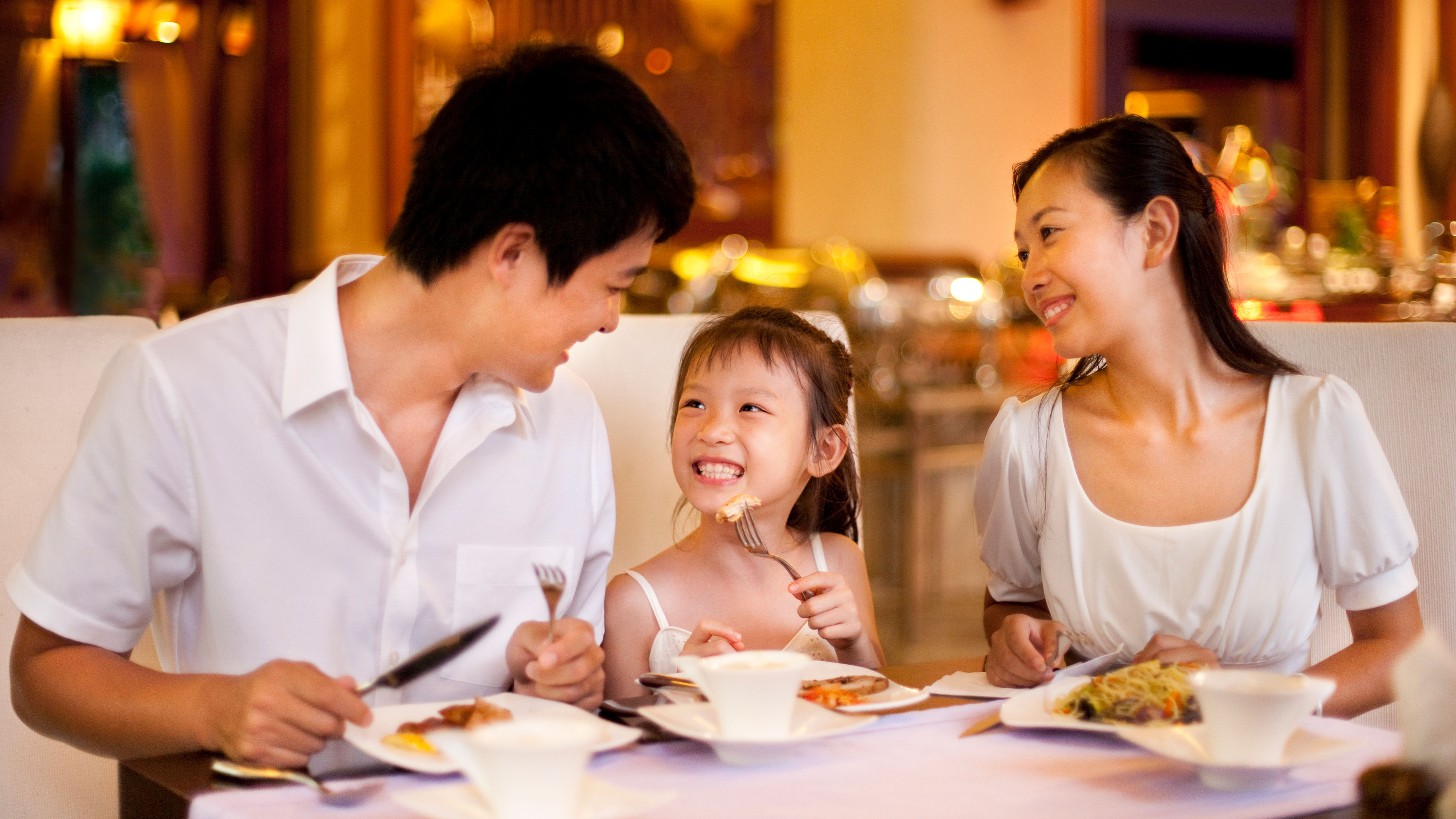 A family sits together in a restaurant, happily enjoying a variety of meals and dishes.