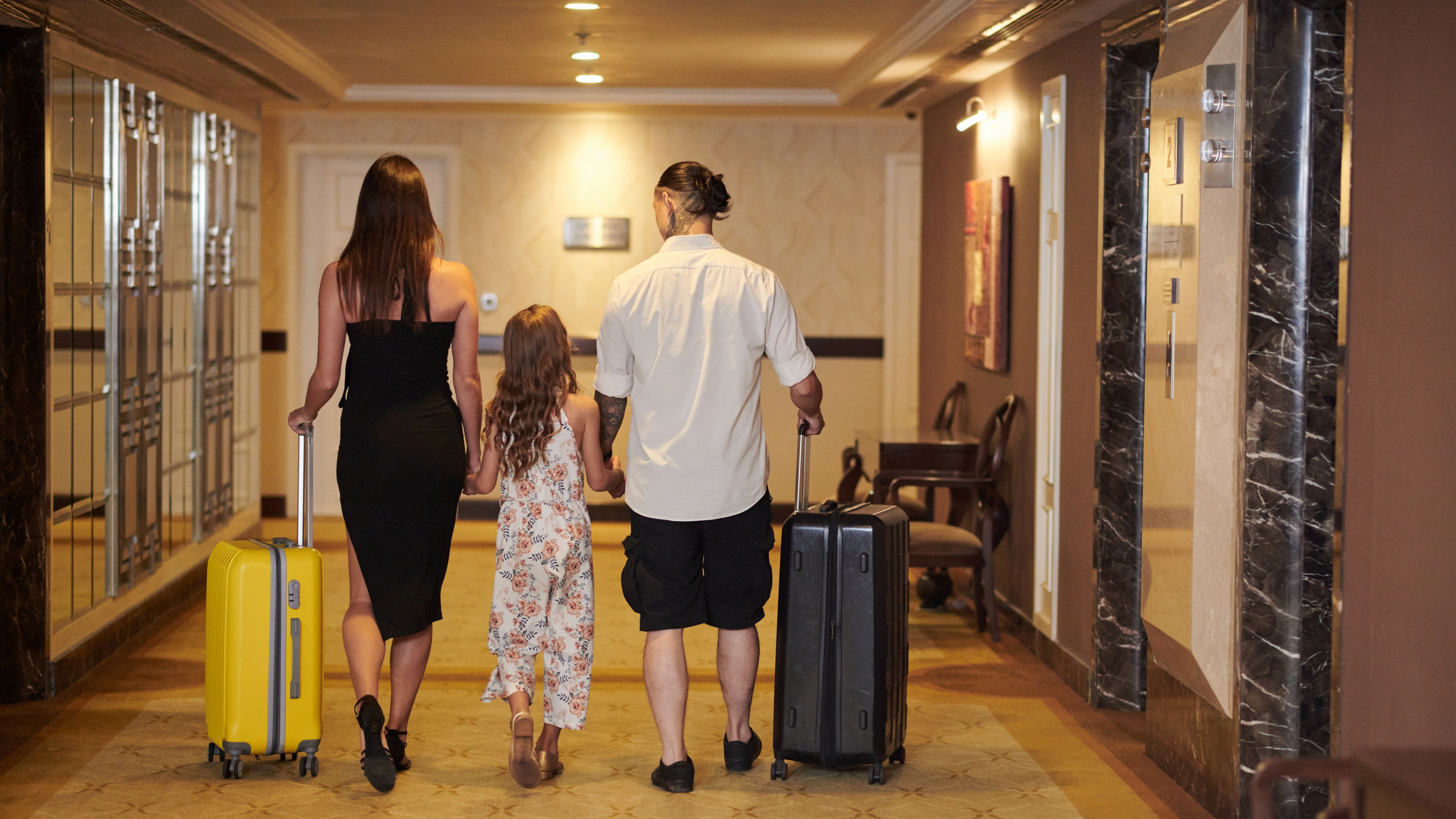 A family of three walking through a hotel aisle 