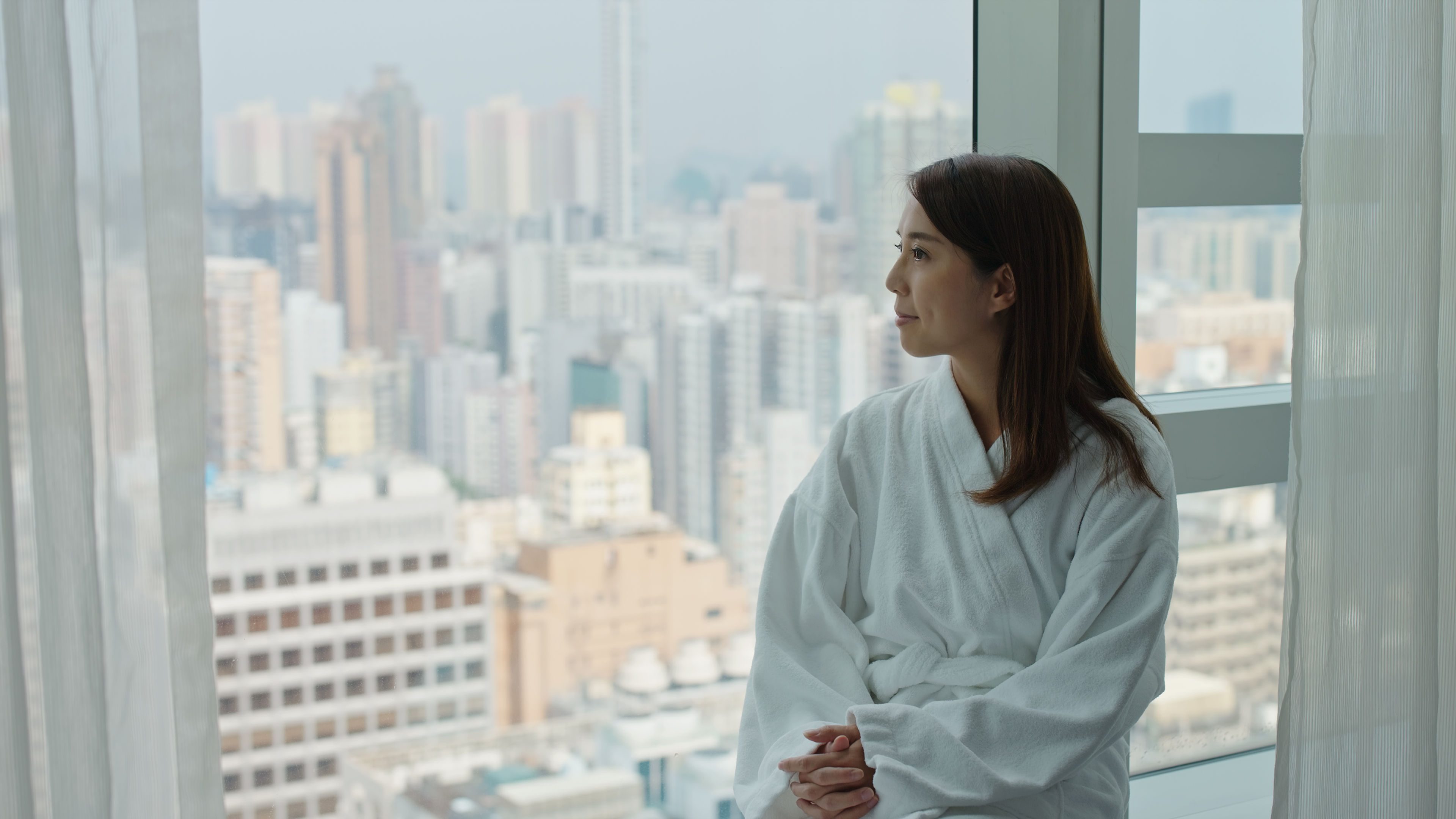 A young woman enjoying view from a hotel room 