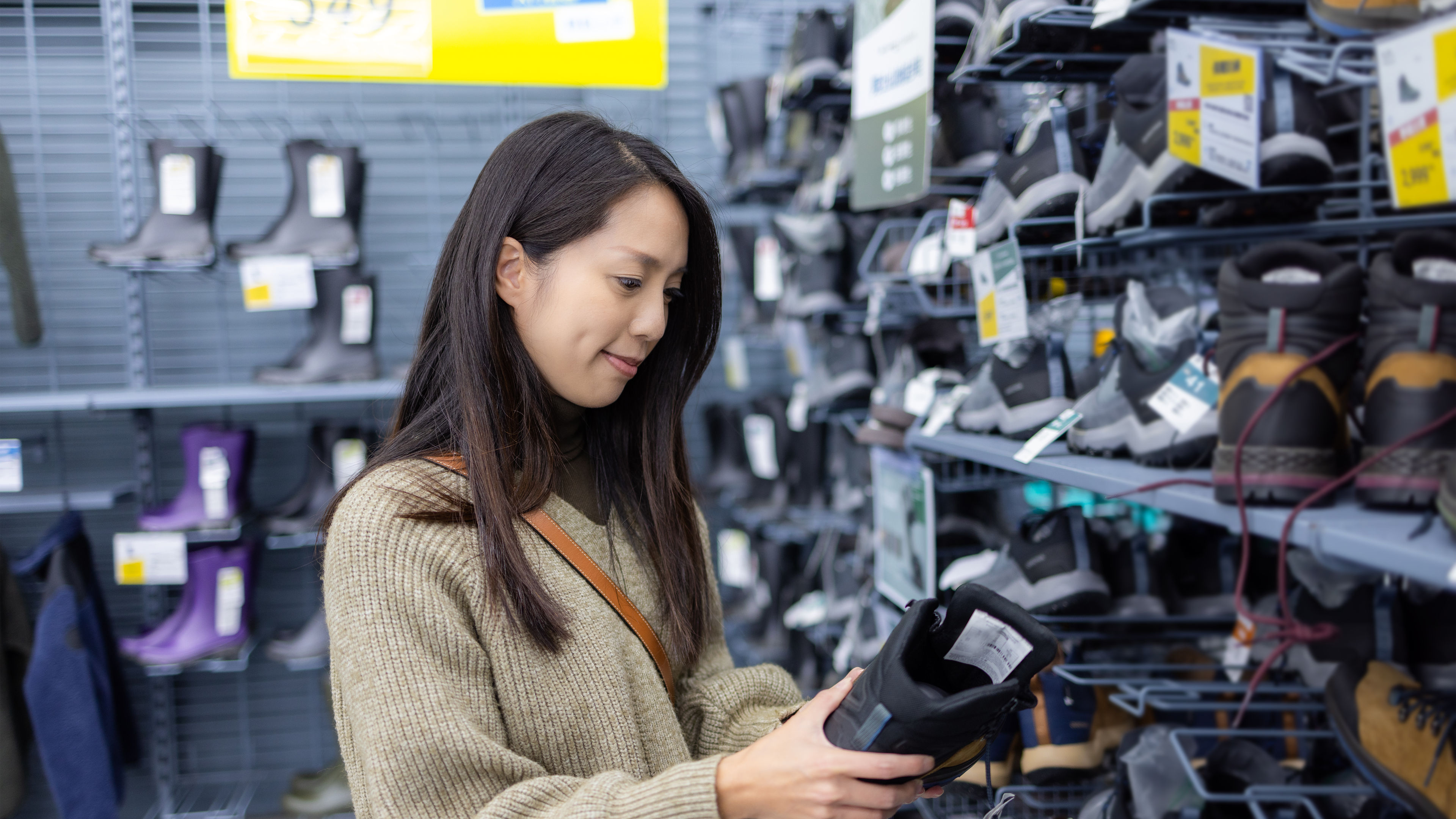 A happy woman looking at a pair of shoes in a shop 
