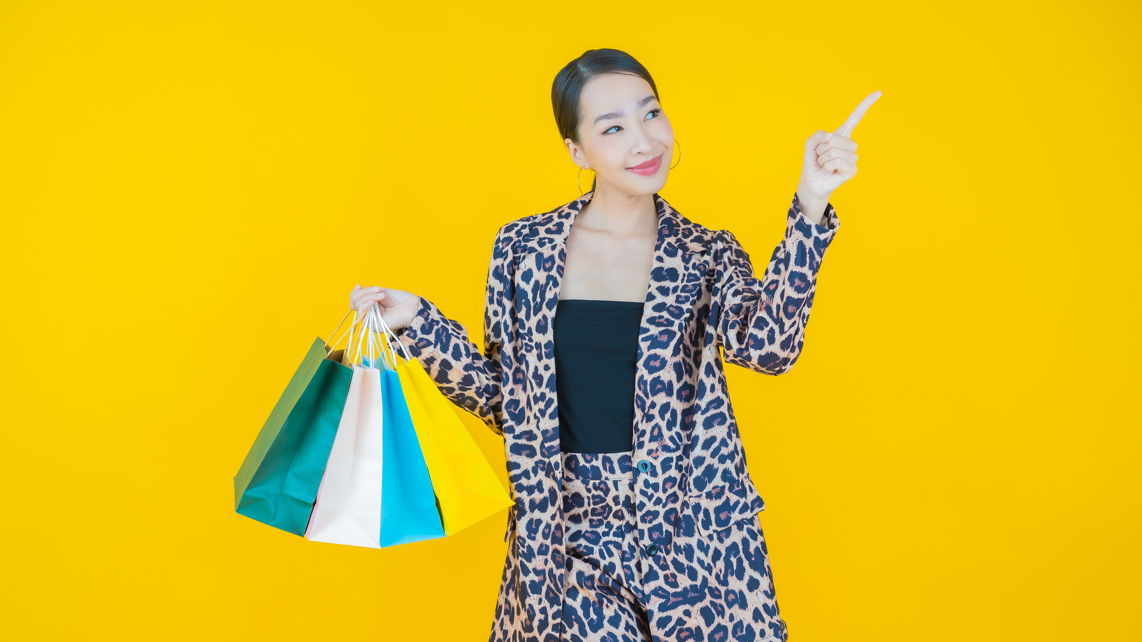 A woman wearing an animal-printed dress with shopping bags in hand 