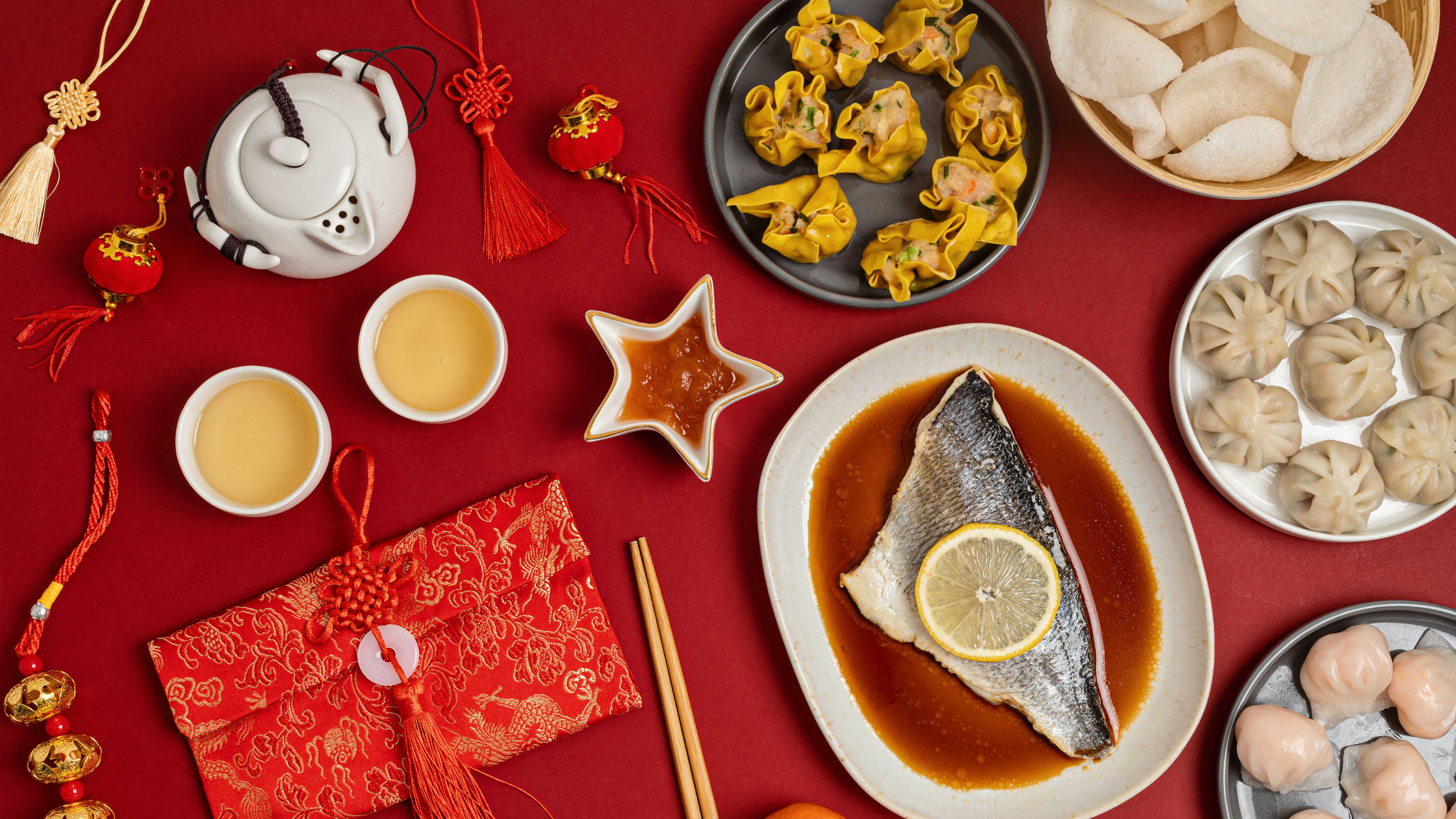 A festive table set with traditional Chinese New Year foods, including dumplings, fish, and symbolic red decorations 