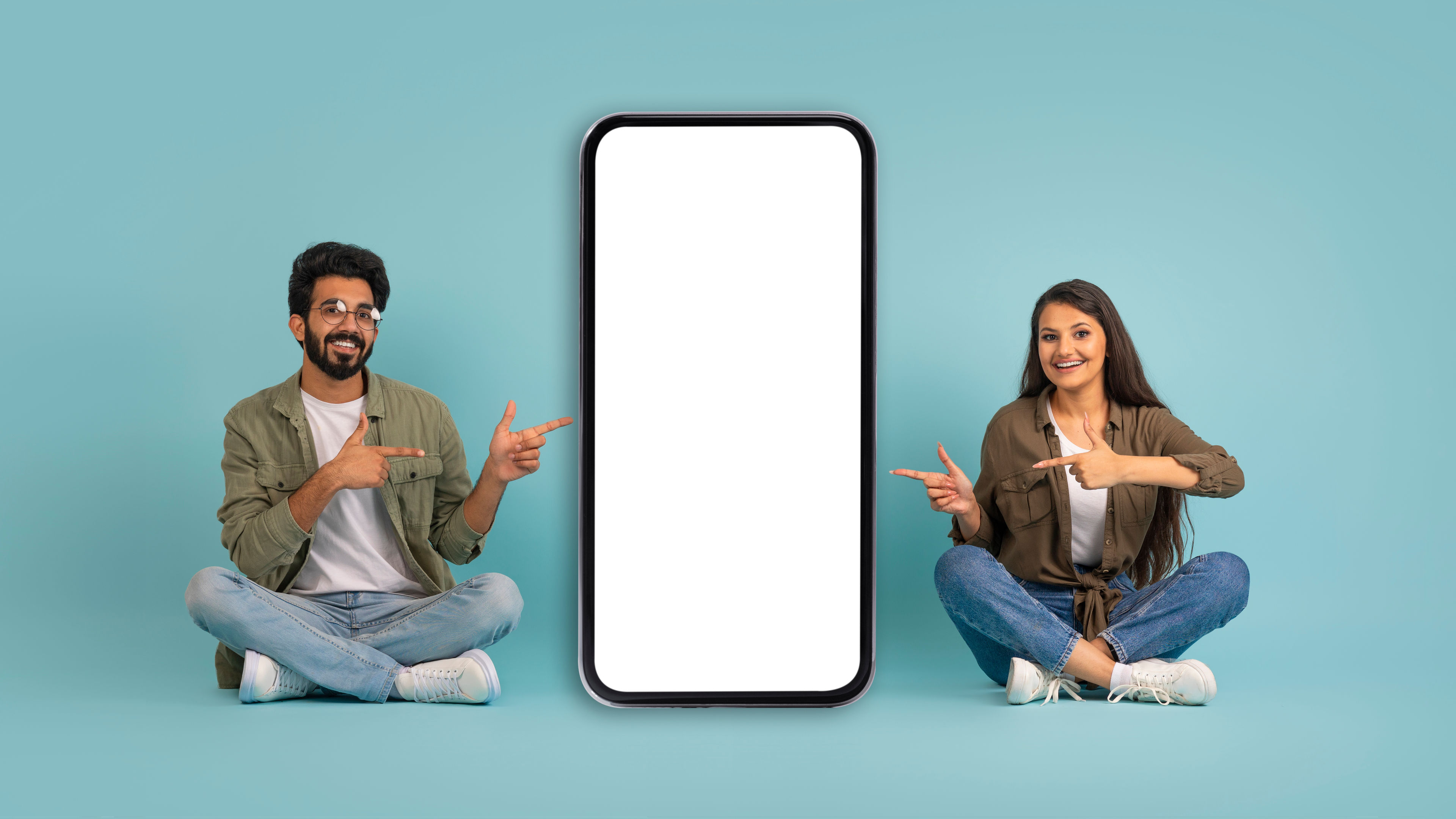 A happy couple pointing to a white screen 
