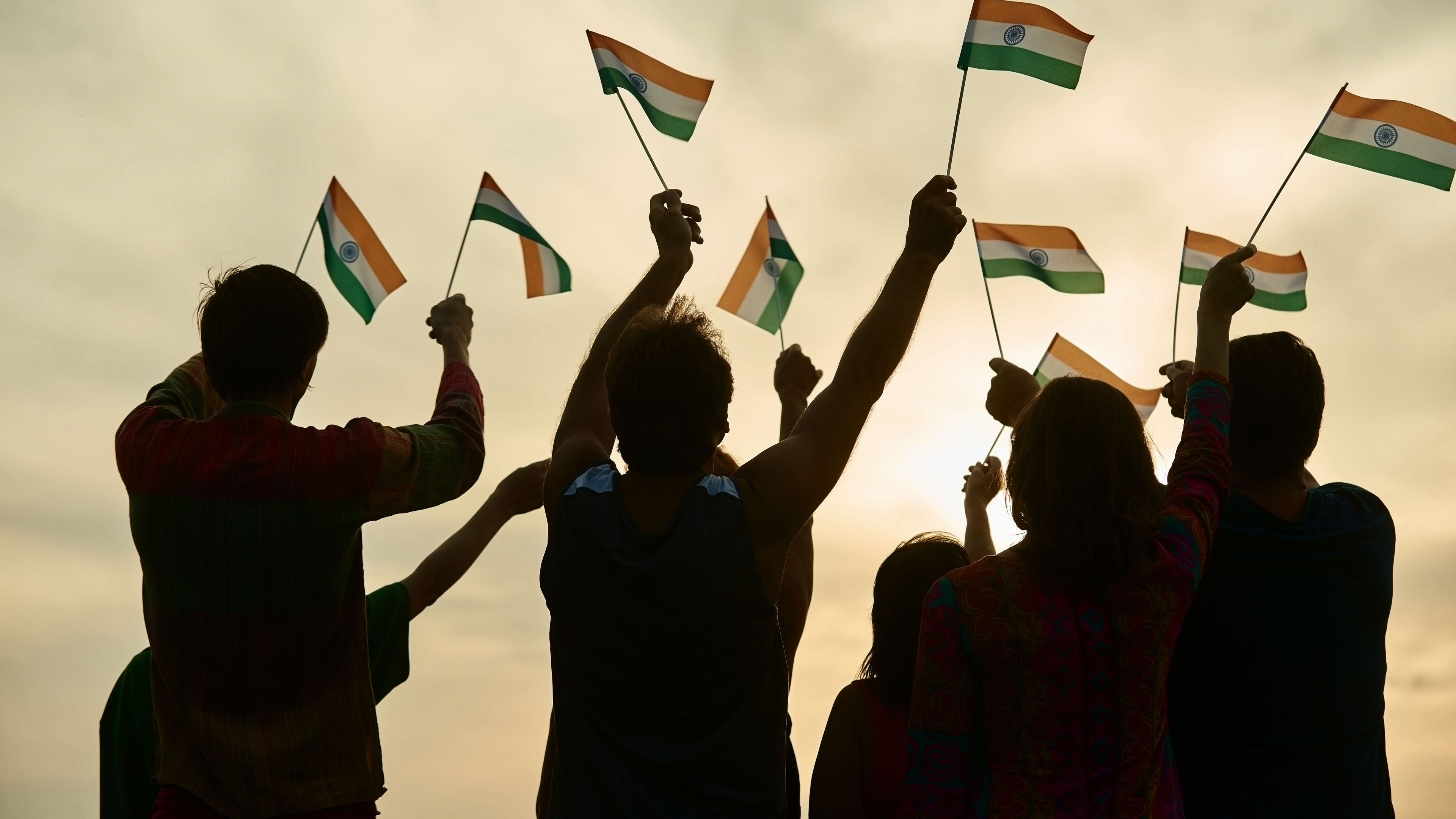 A group of Indian patriots proudly waves the national flag outdoors, their faces filled with pride and enthusiasm. 