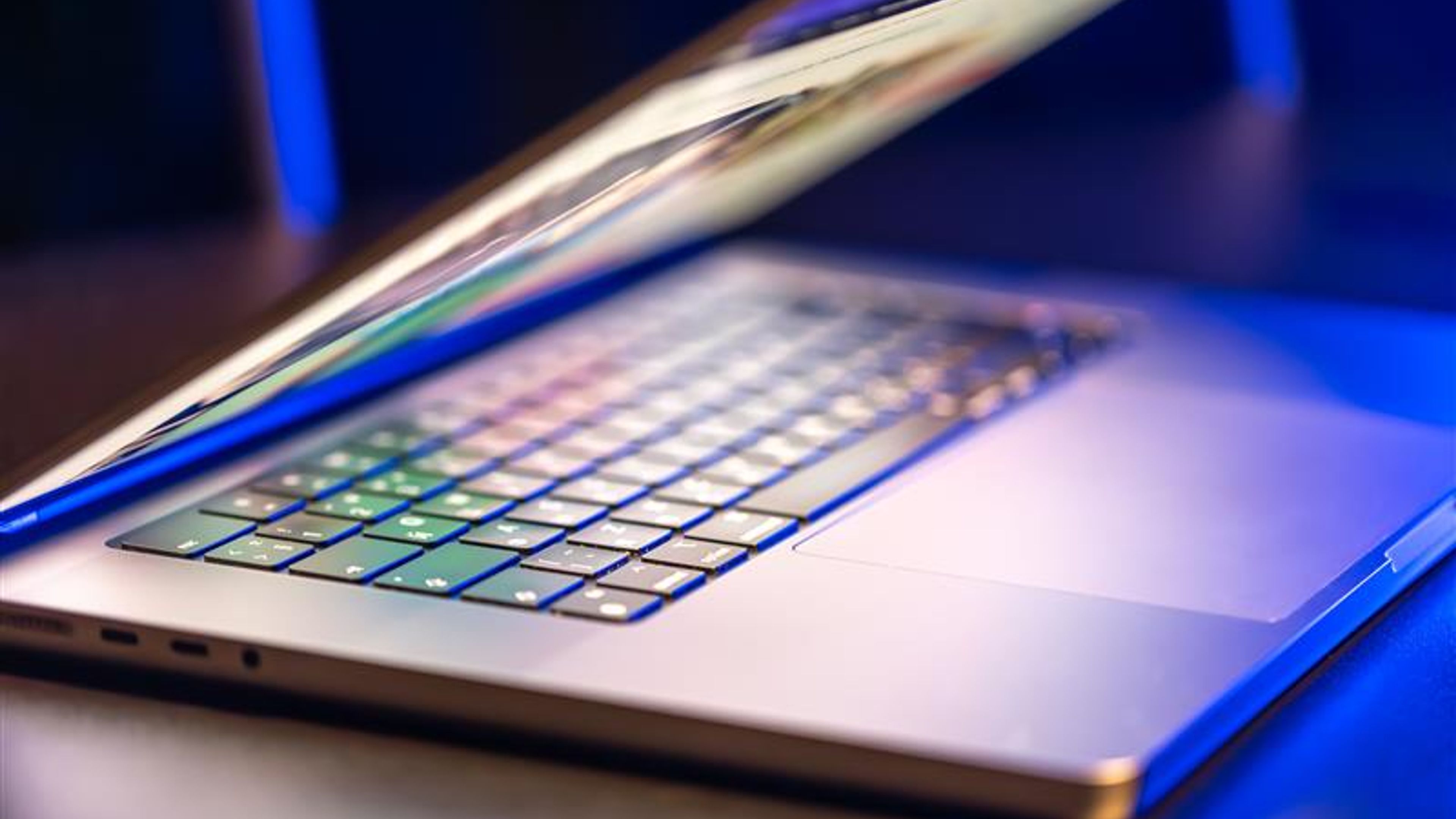 A laptop computer with a half-open screen on a dark background. 