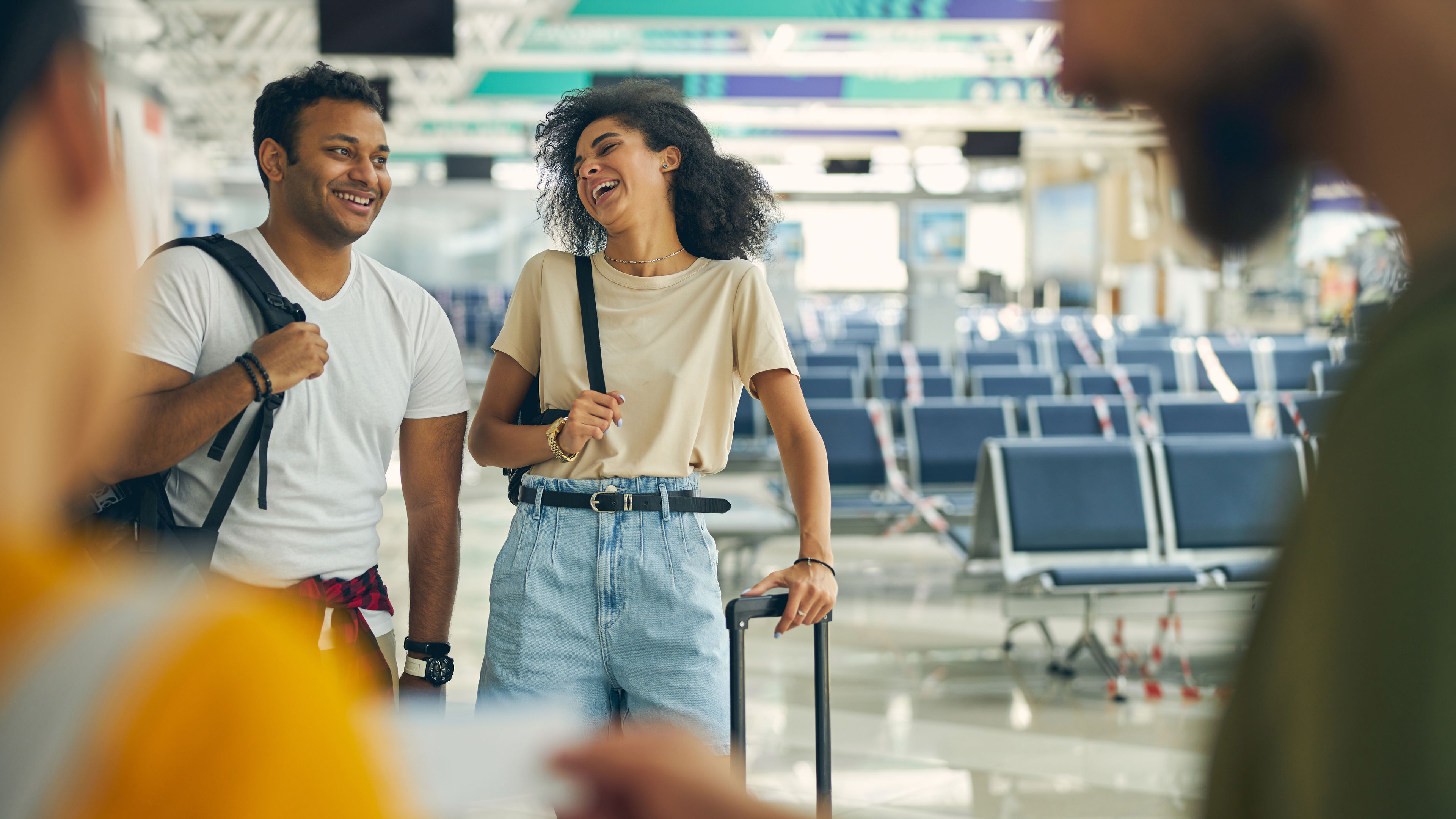 A smiling Indian man and a young woman share a lighthearted moment in the bustling international terminal 