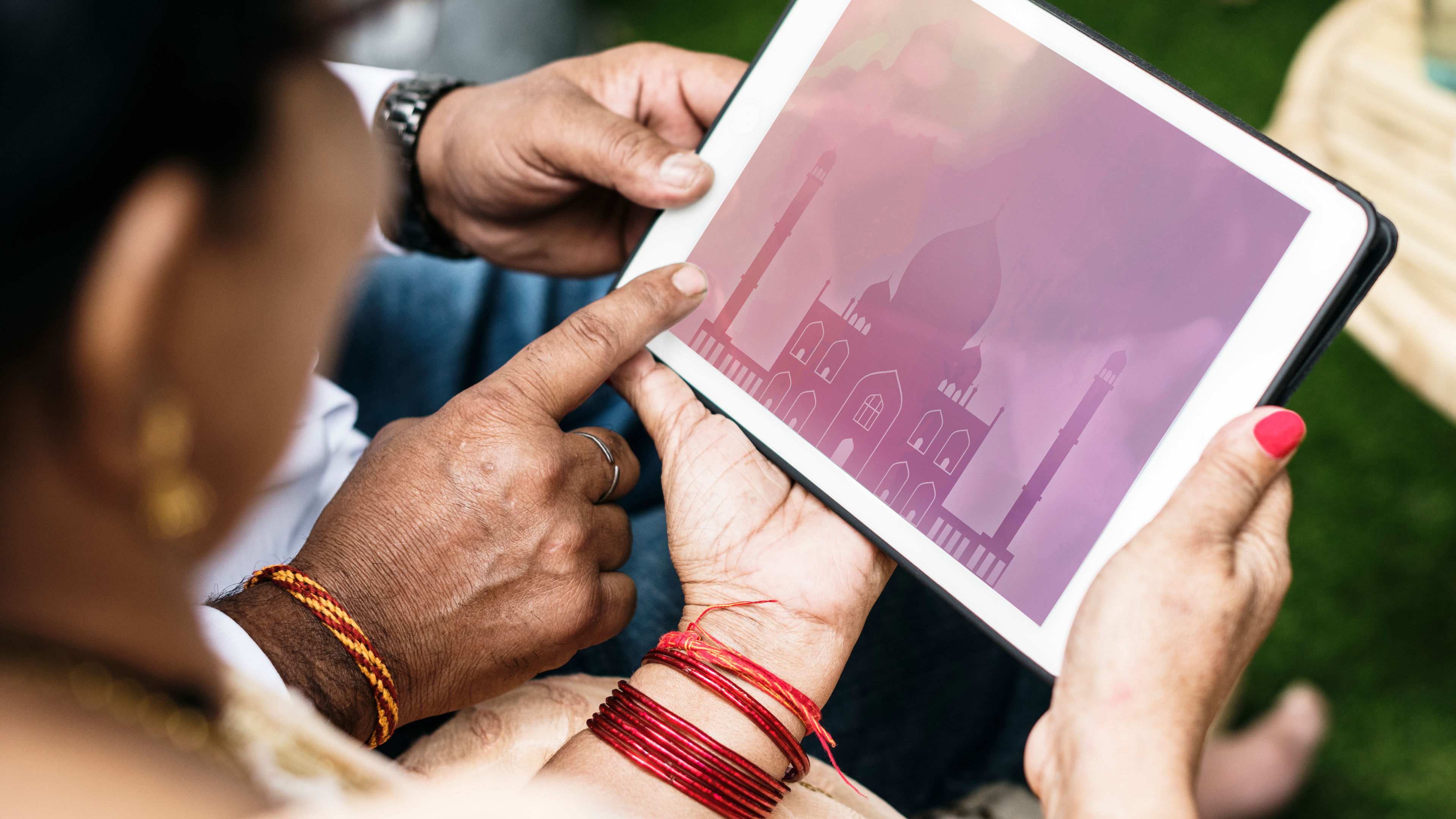 An Indian family gathers around a tablet, engaged in a shared learning experience. The parents sit close, guiding their children as they explore educational content. 