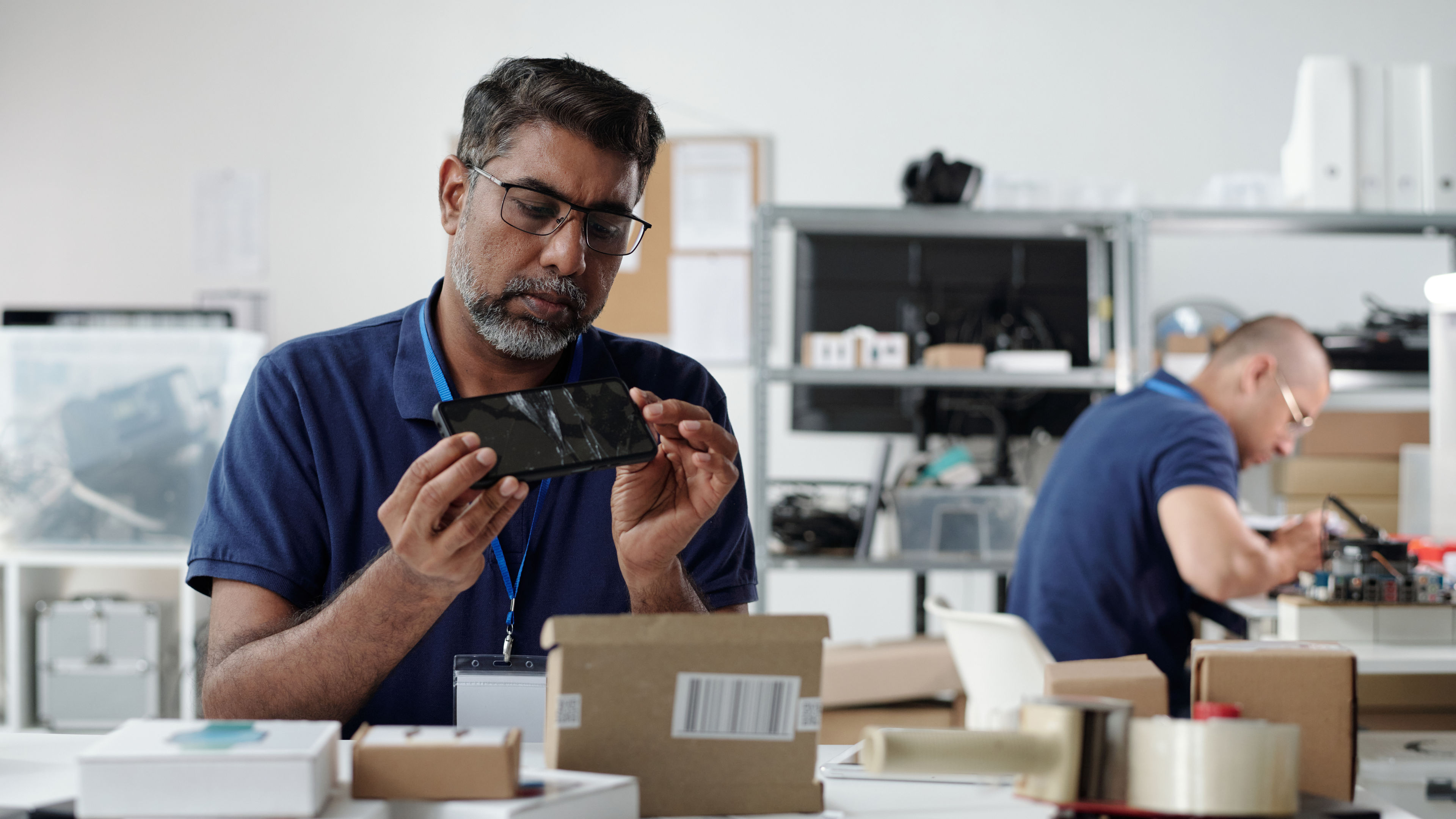 Concentrated Engineer Examining Mobile Device in Workshop 