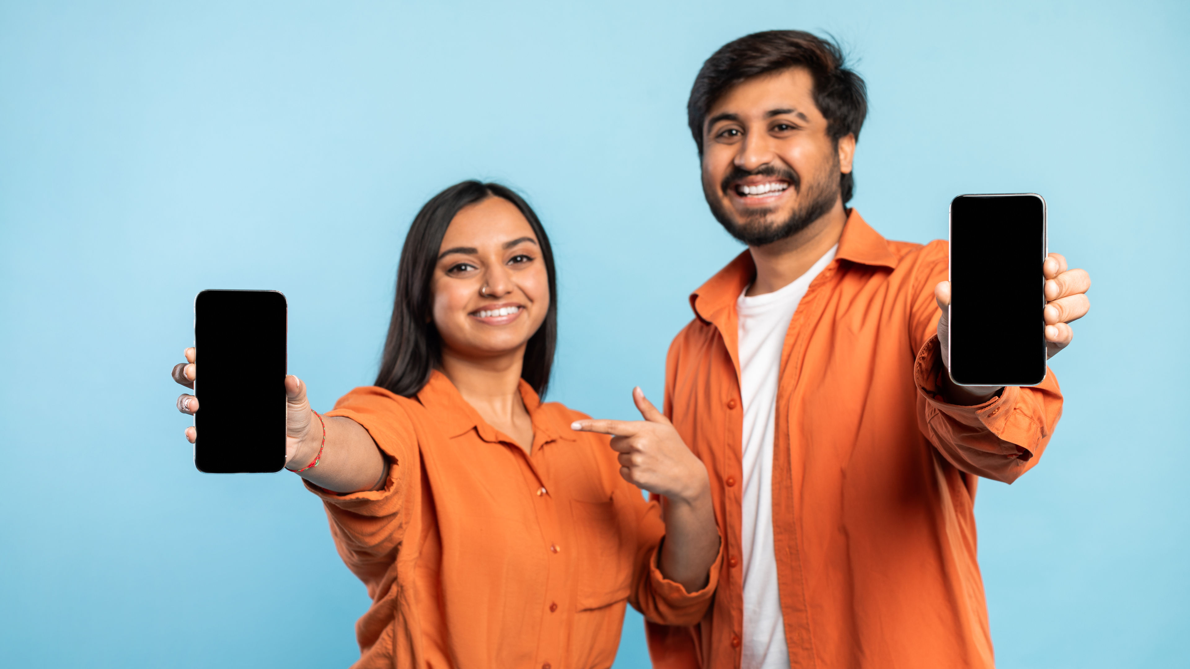 Couple showing a smartphone screen on blue 