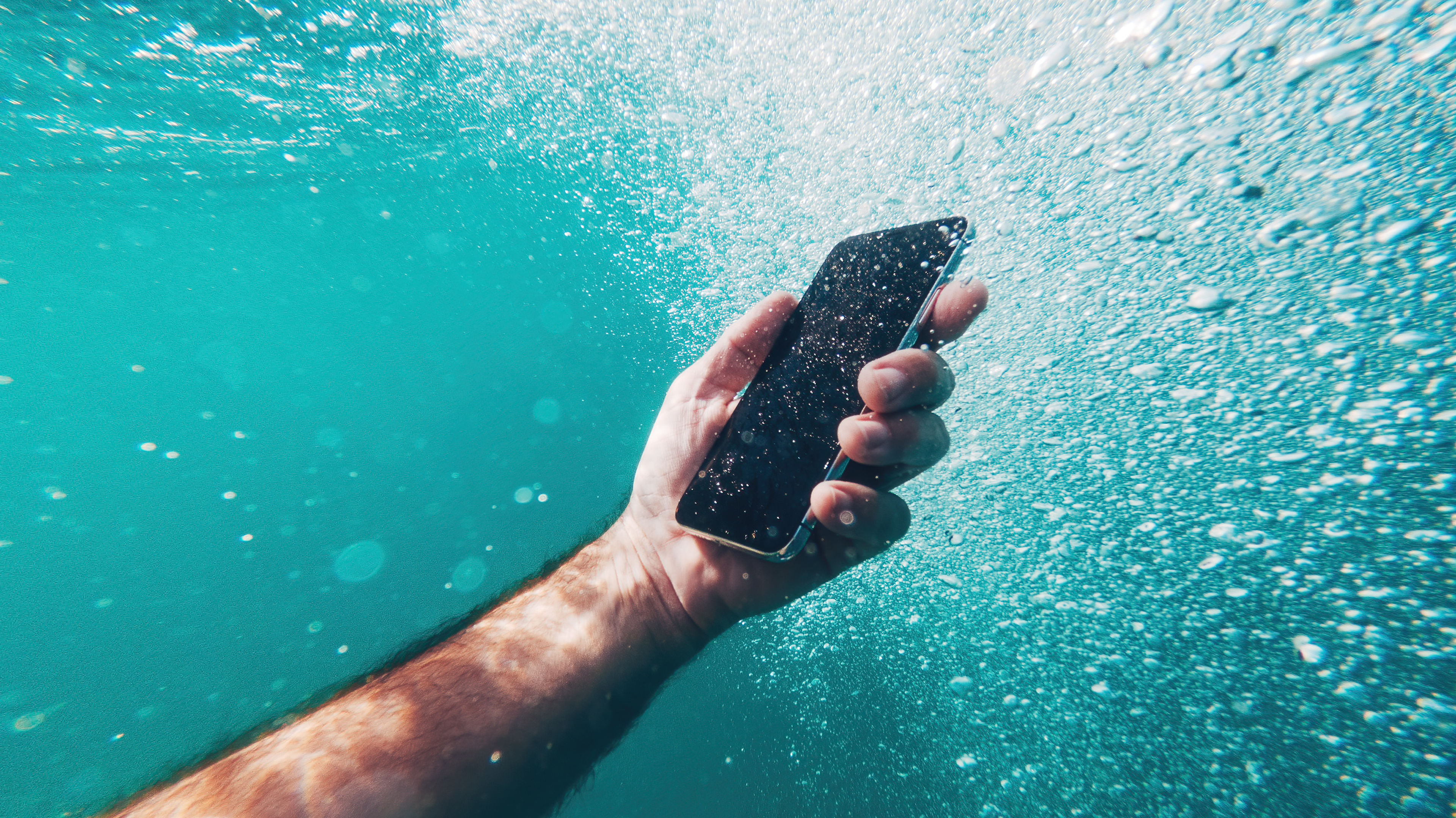 Man using smartphone device underwater in deep blue sea during summer holiday vacation 