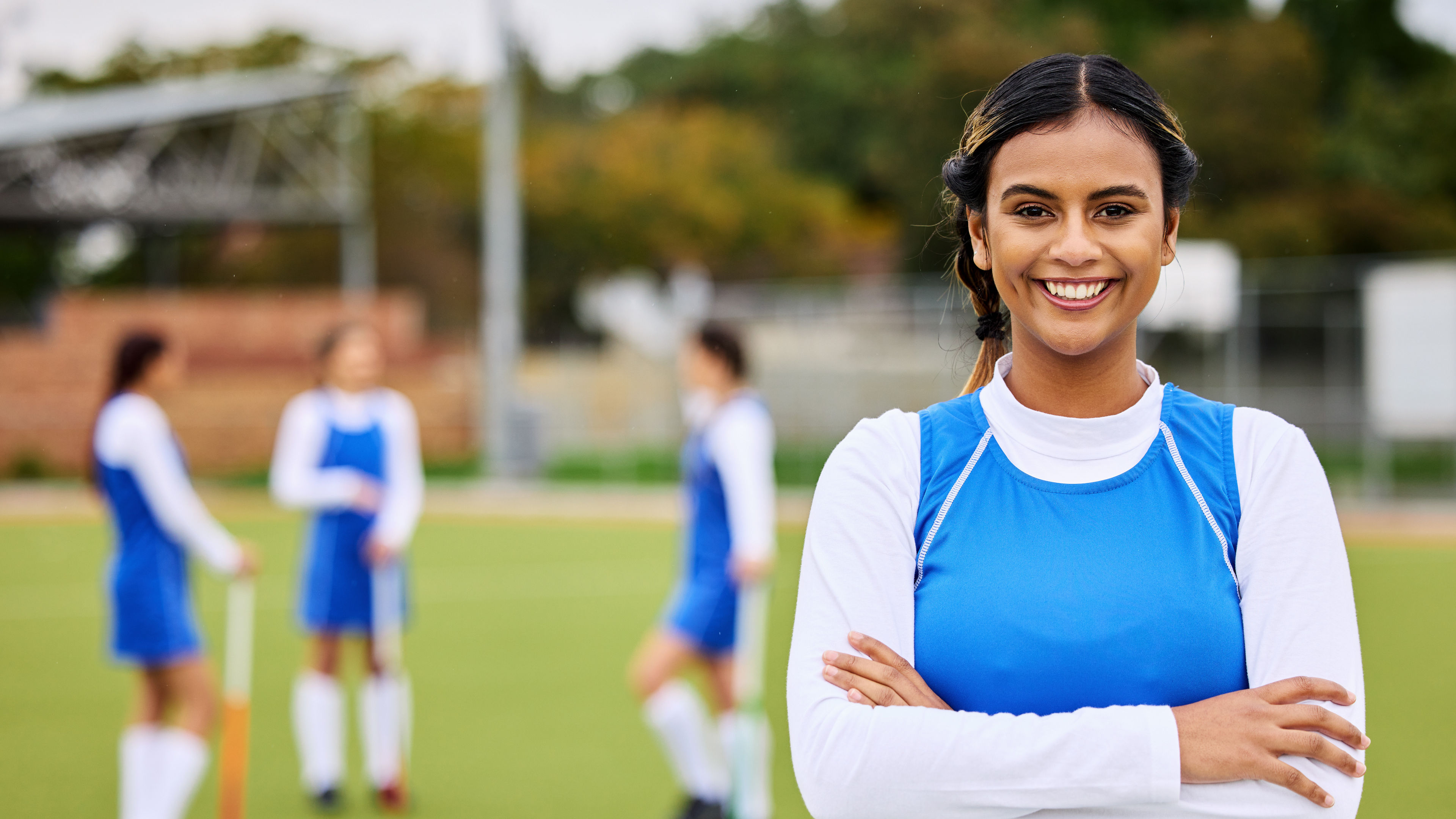 A female field hockey player smiling confidently during a portrait session for sports.
