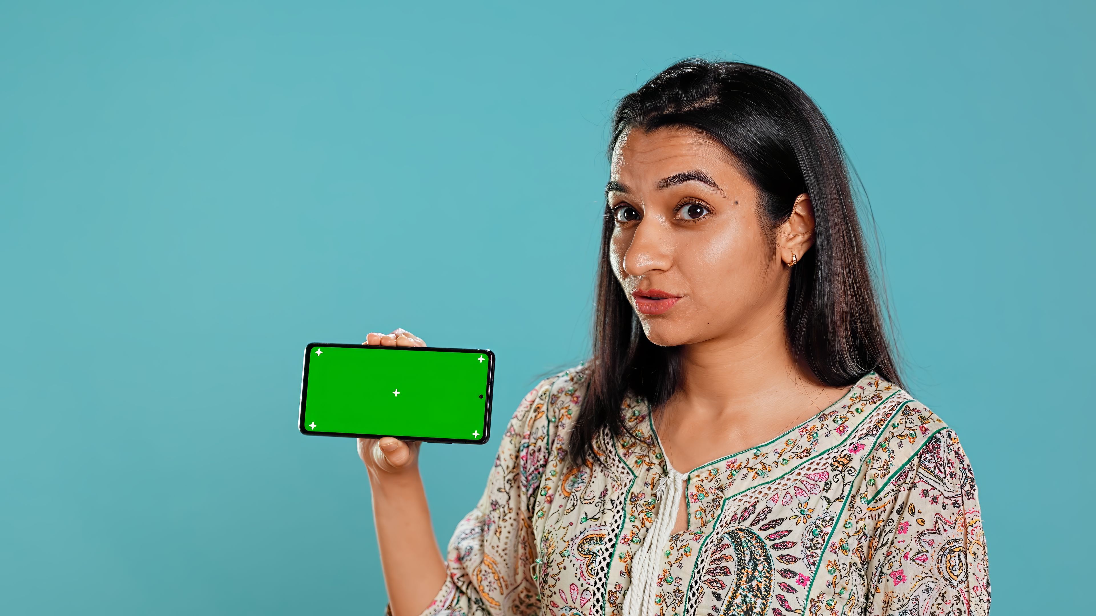 Upbeat girl holding phone with green screen 