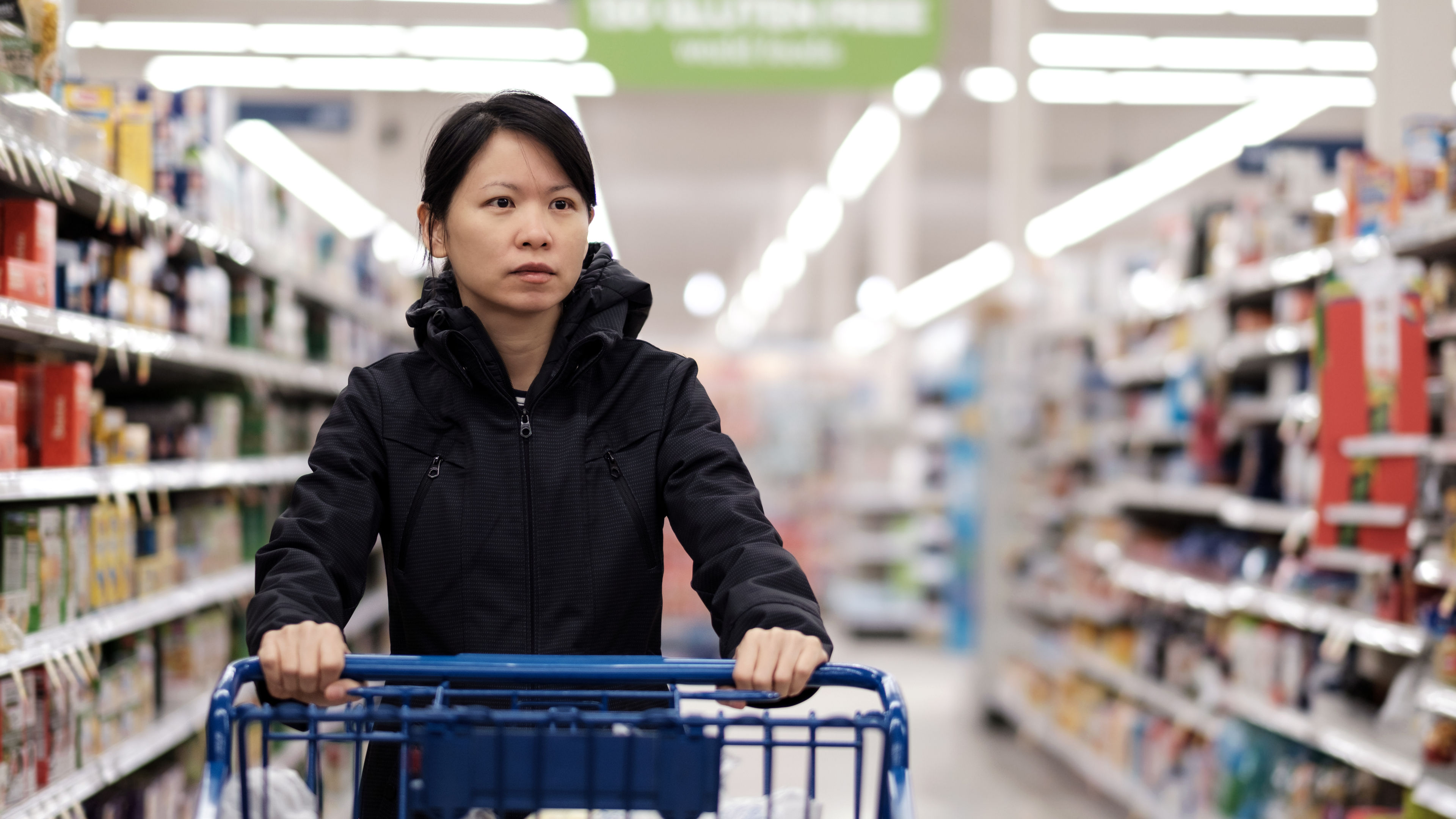 An Asian woman shopping for groceries in a shopping market.