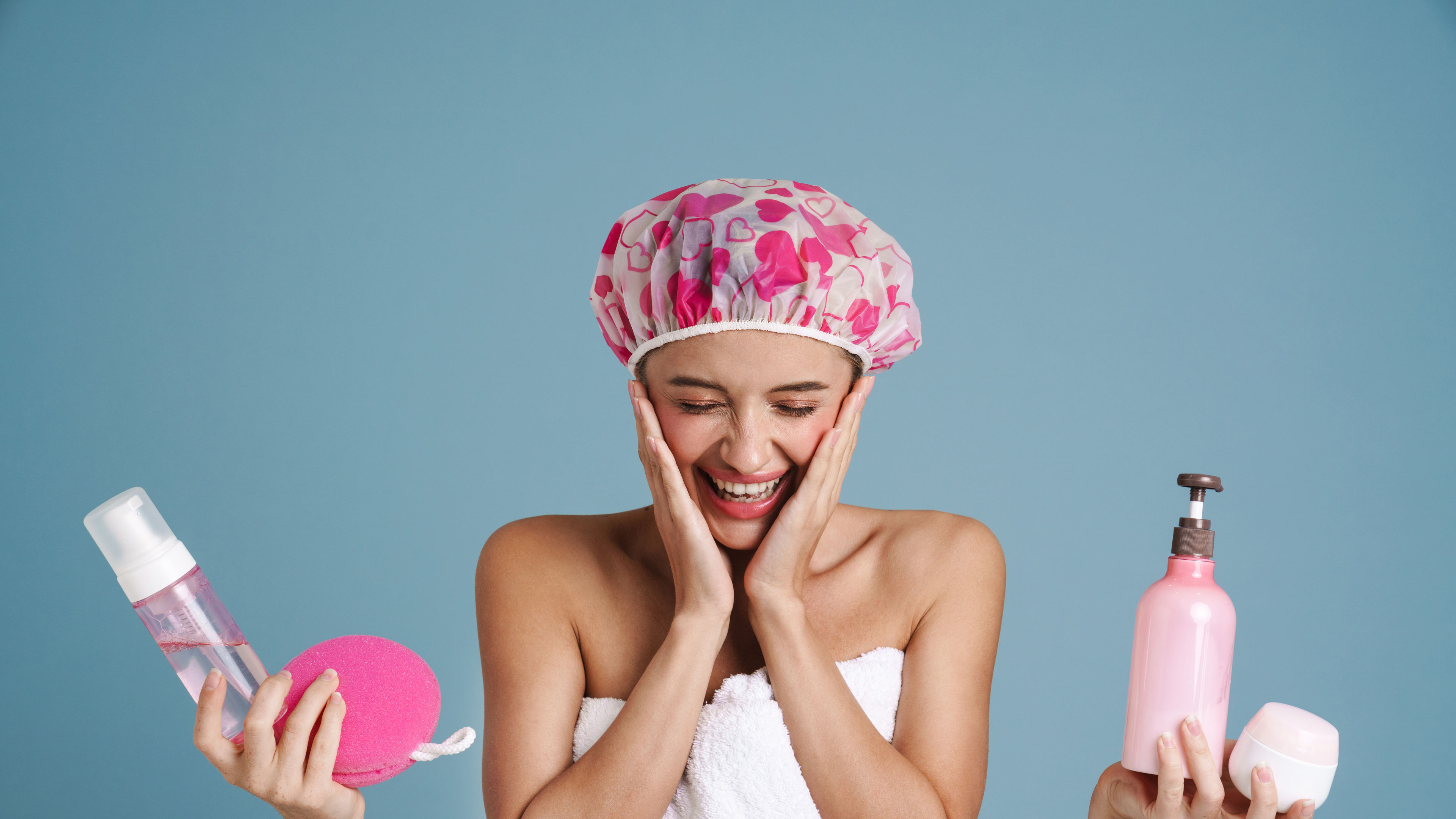 A young woman laughs while surrounded by cosmetic products.