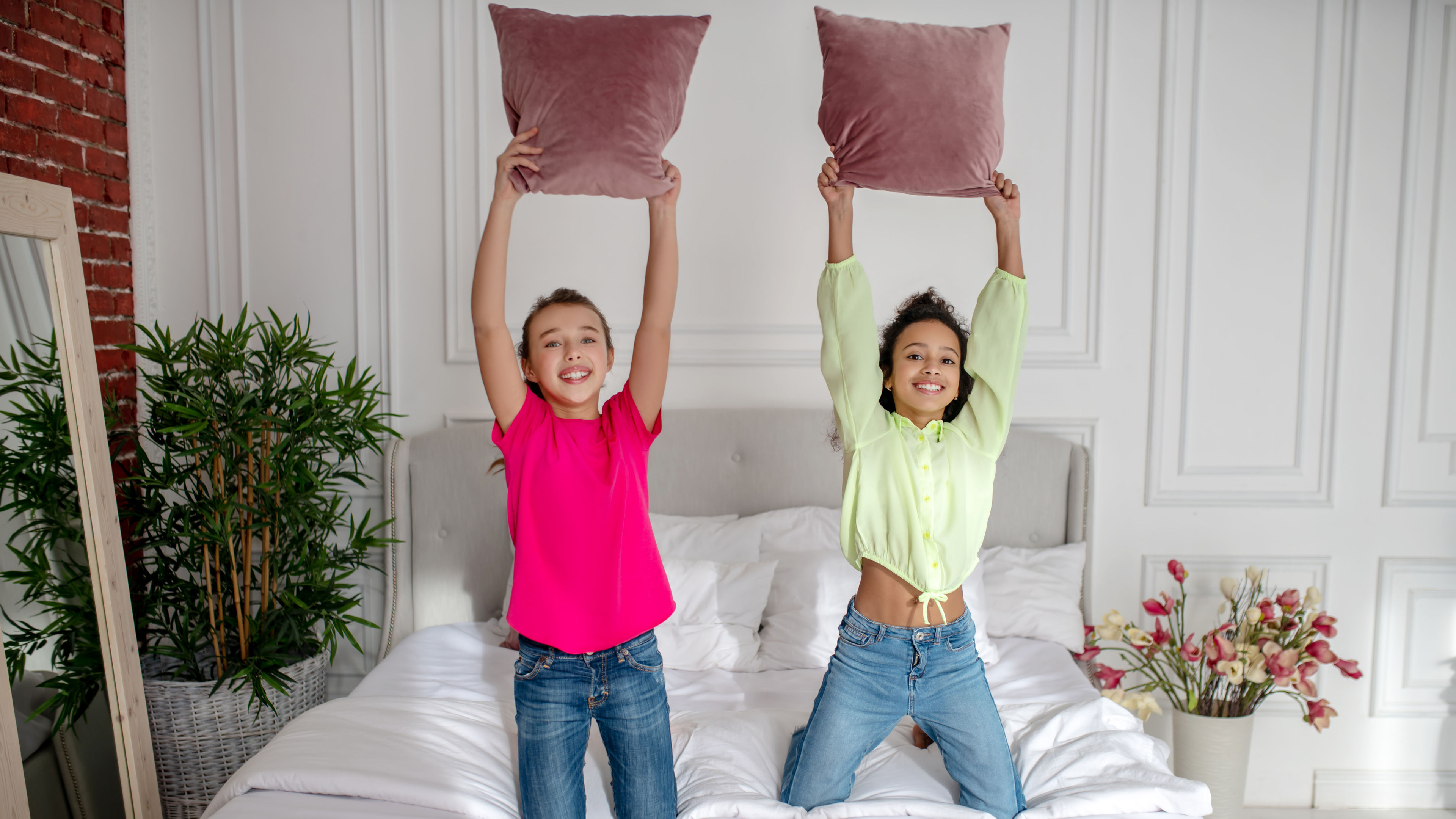 Two pretty girls are holding pillows, enjoying a fun moment together.