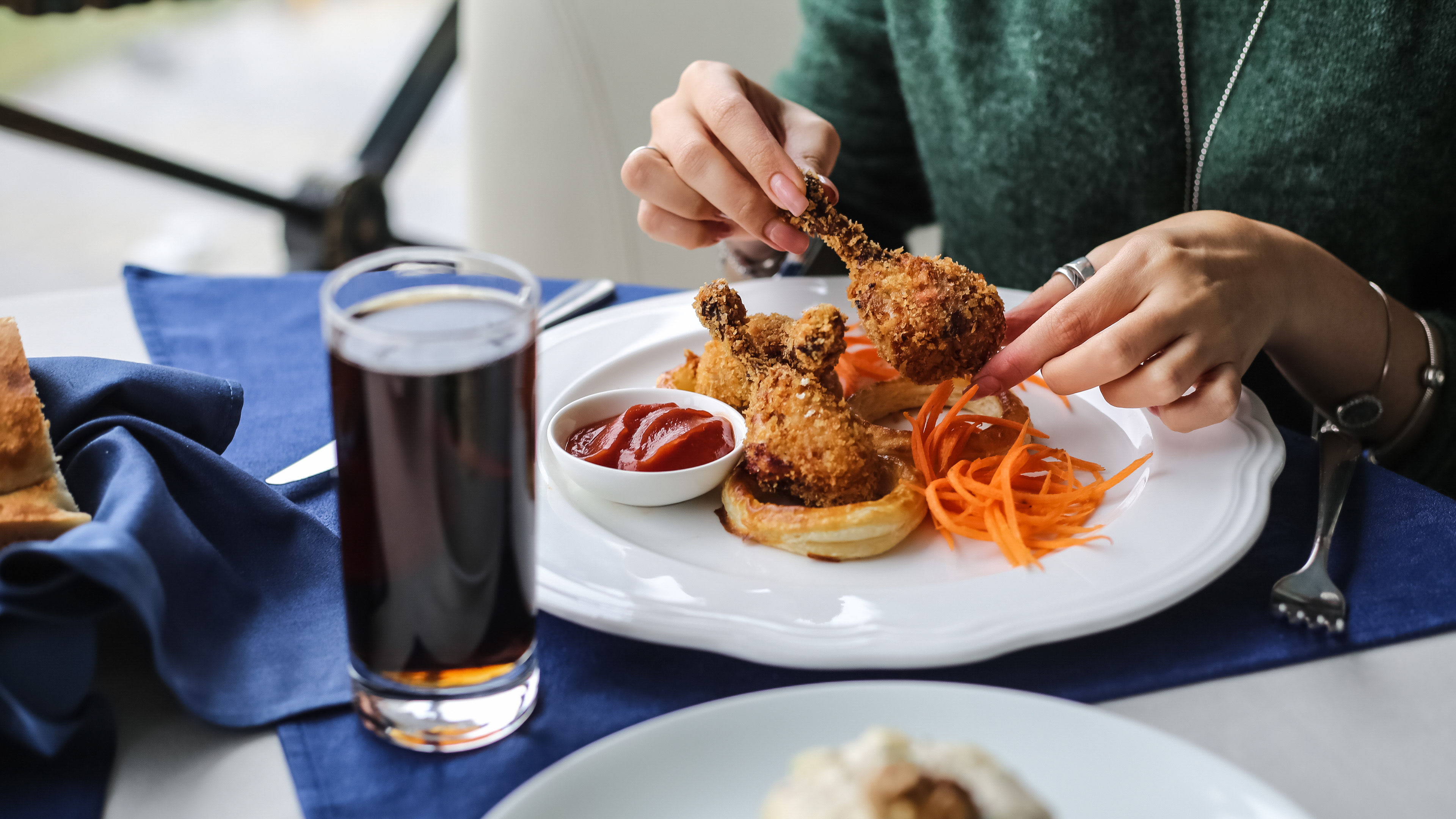 Seorang wanita menikmati kaki ayam goreng rangup dalam adunan, merakam kegembiraan menikmati makanan selesa yang lazat. 