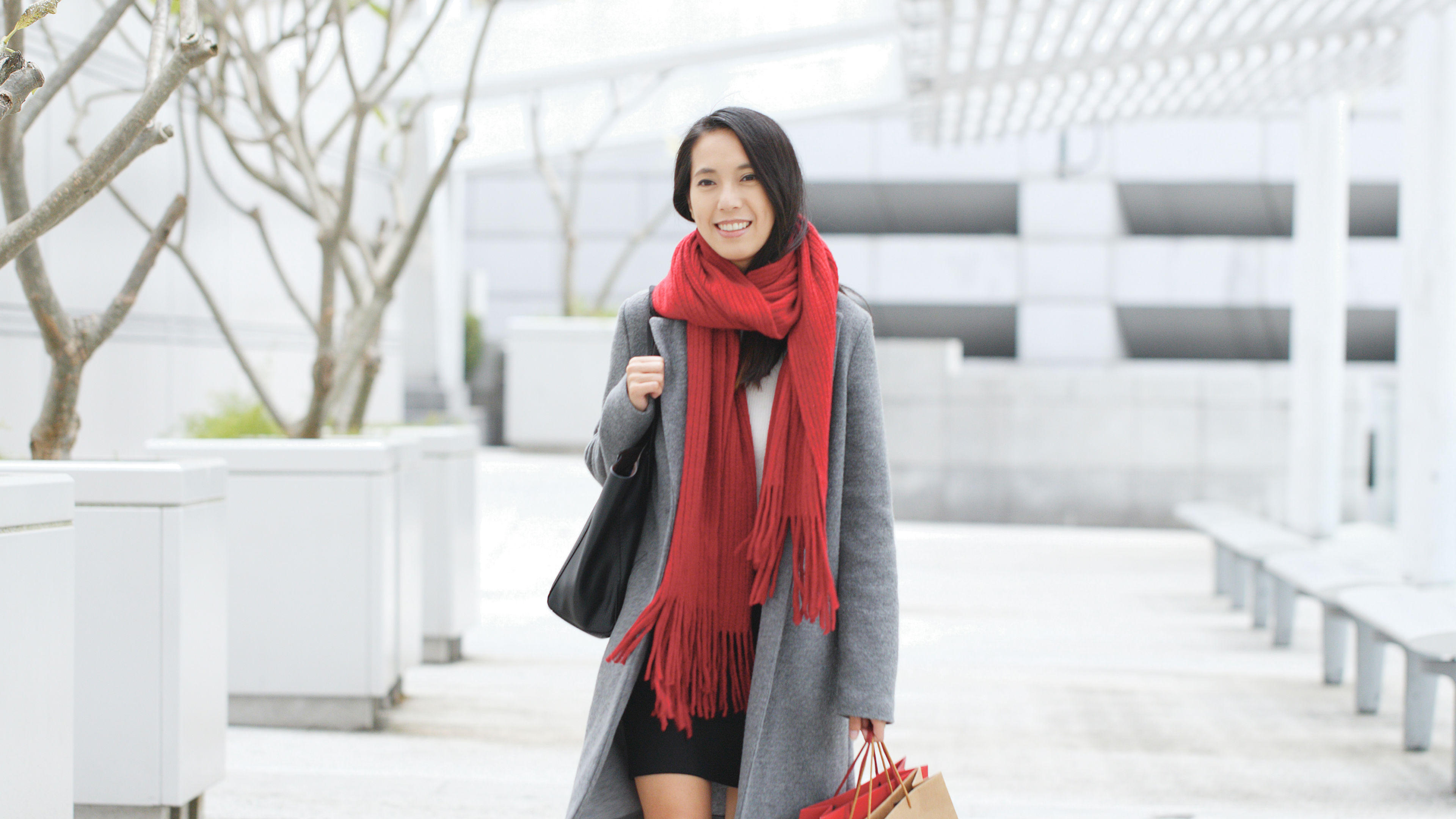 A woman happily goes shopping, carrying paper bags filled with purchases. 