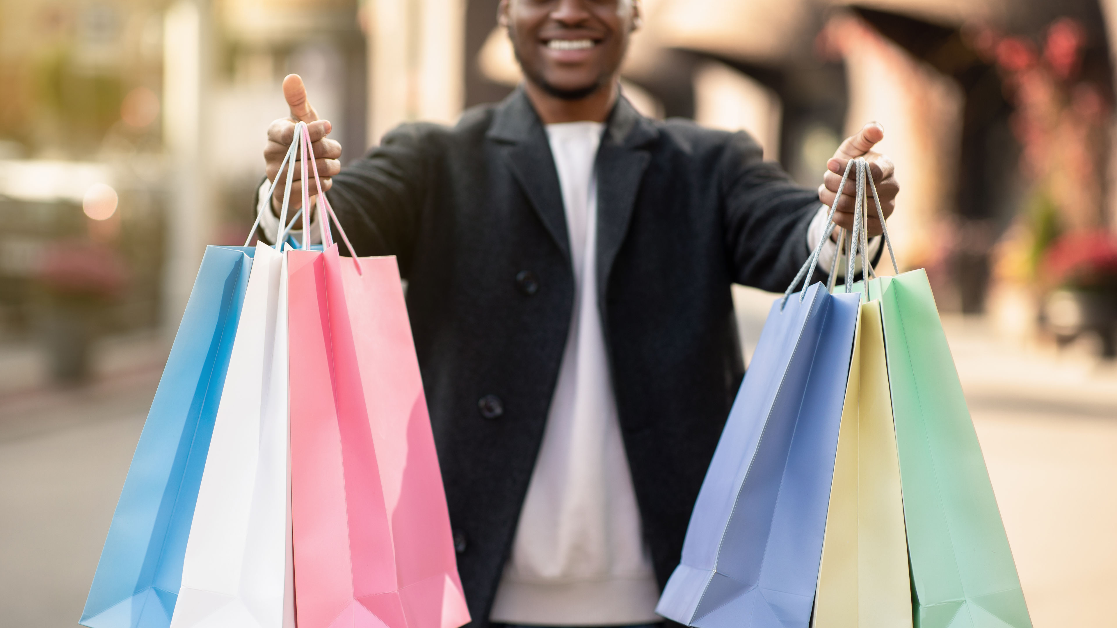 An African American man holding colorful shopping bags.
