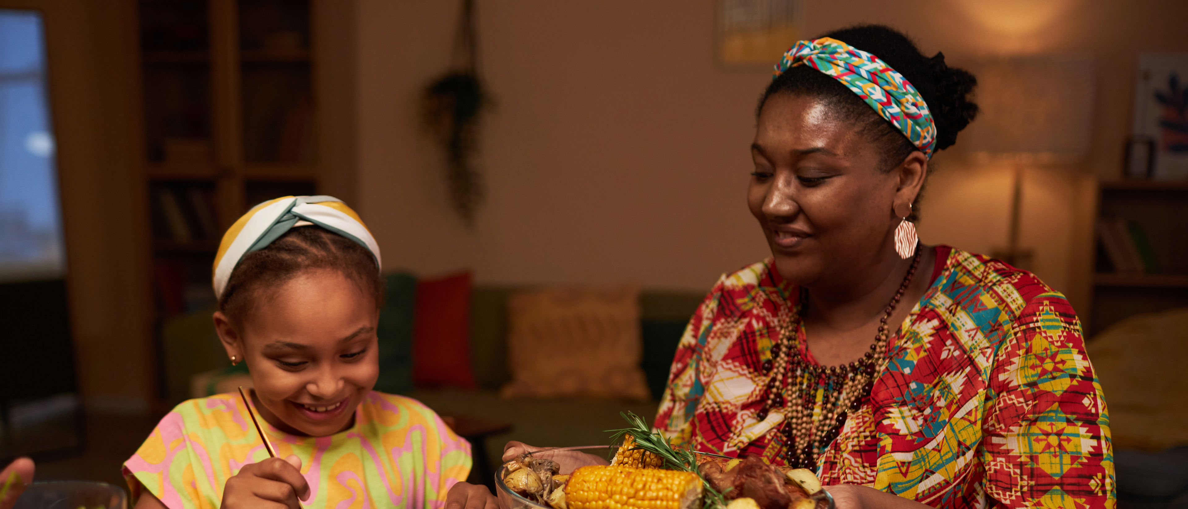 Mother helping daughter to take food from big dish