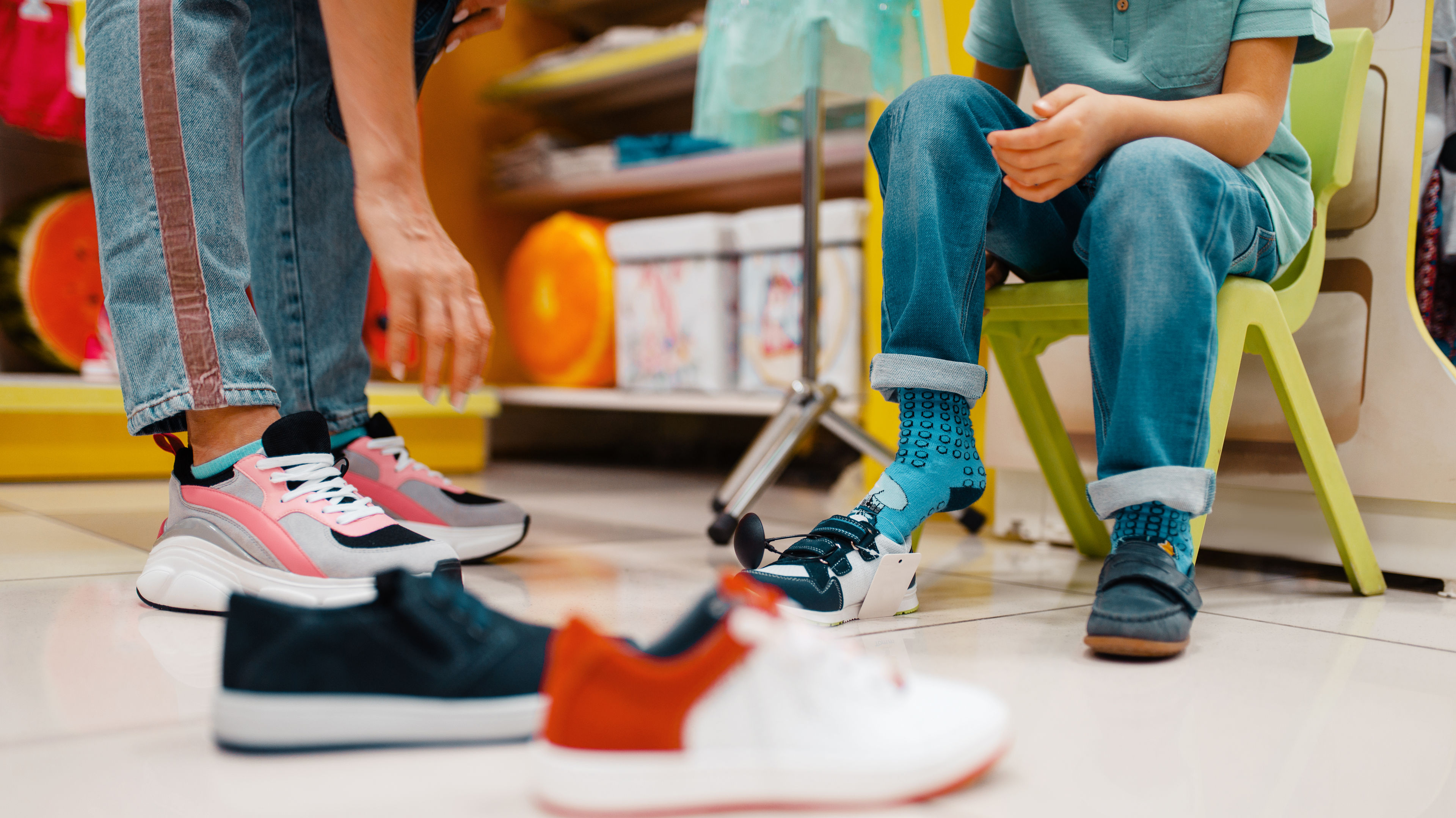 A mother helping her child try on shoes in a store.