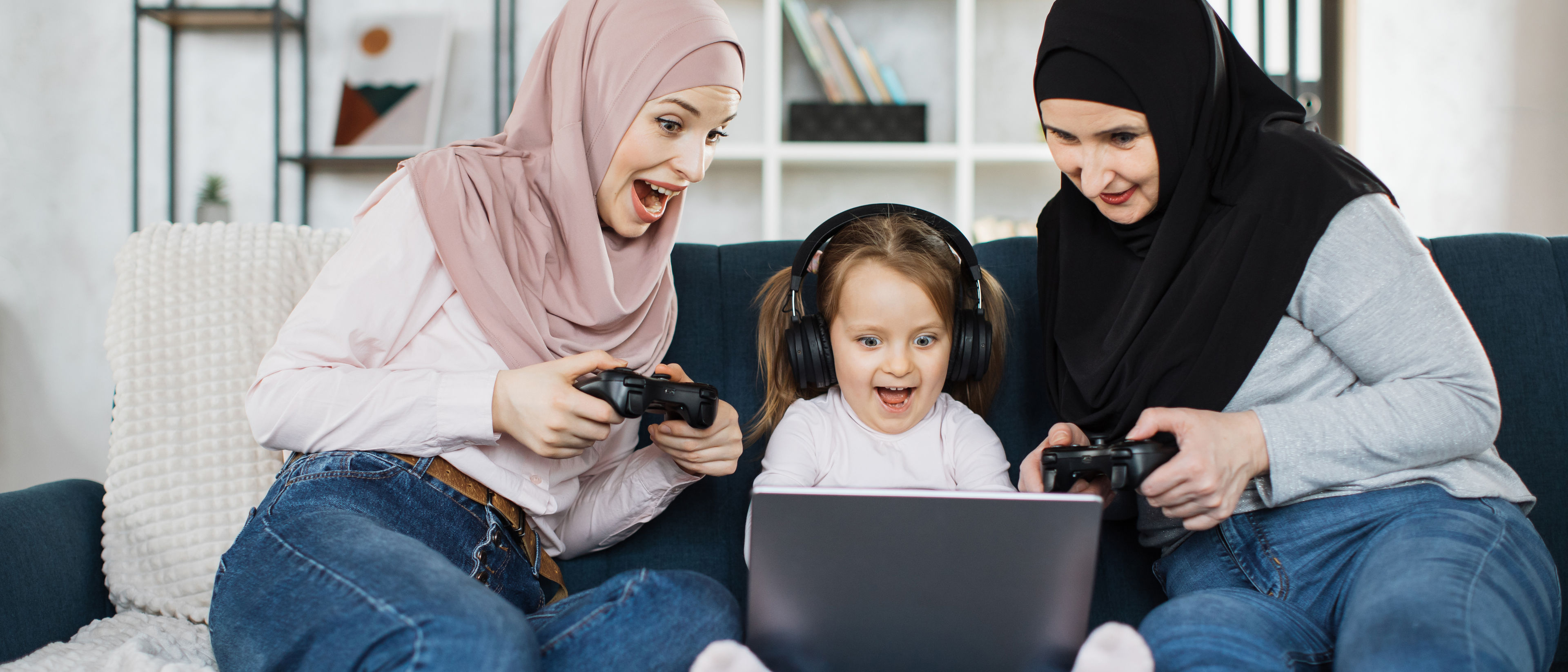 granny, young mom and little cute girl with headphone playing video games