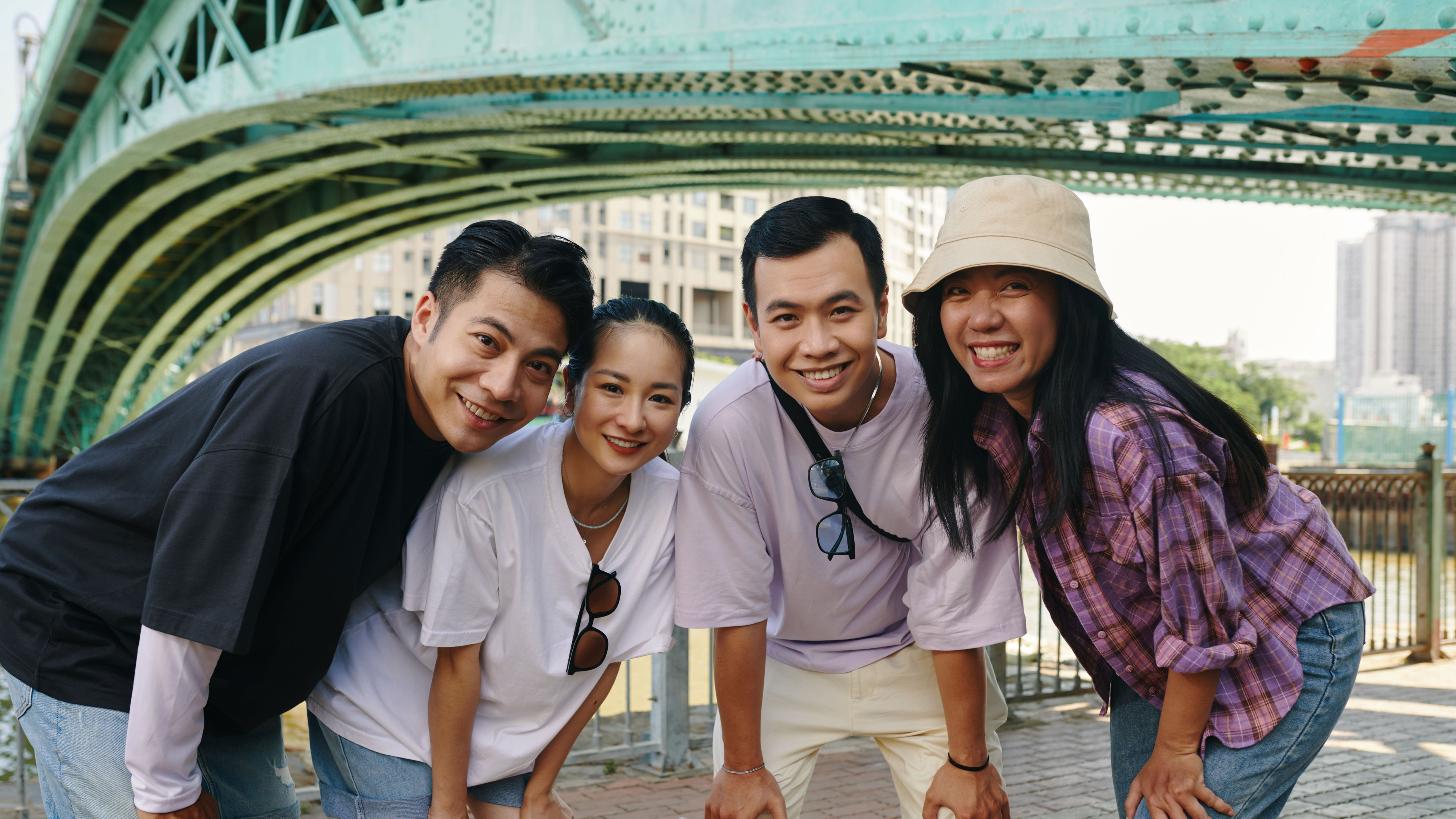 A group of friends smiling and posing under a bridge.