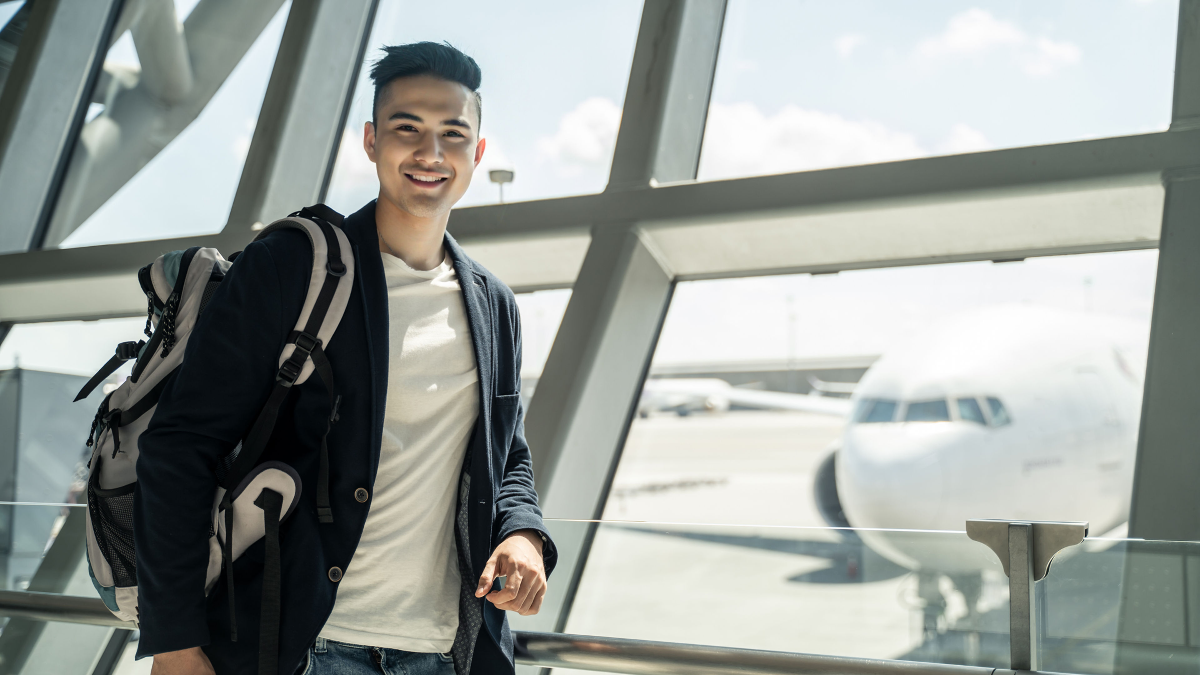 Asian boy waiting to board into airplane, standing in departure terminal in airport.