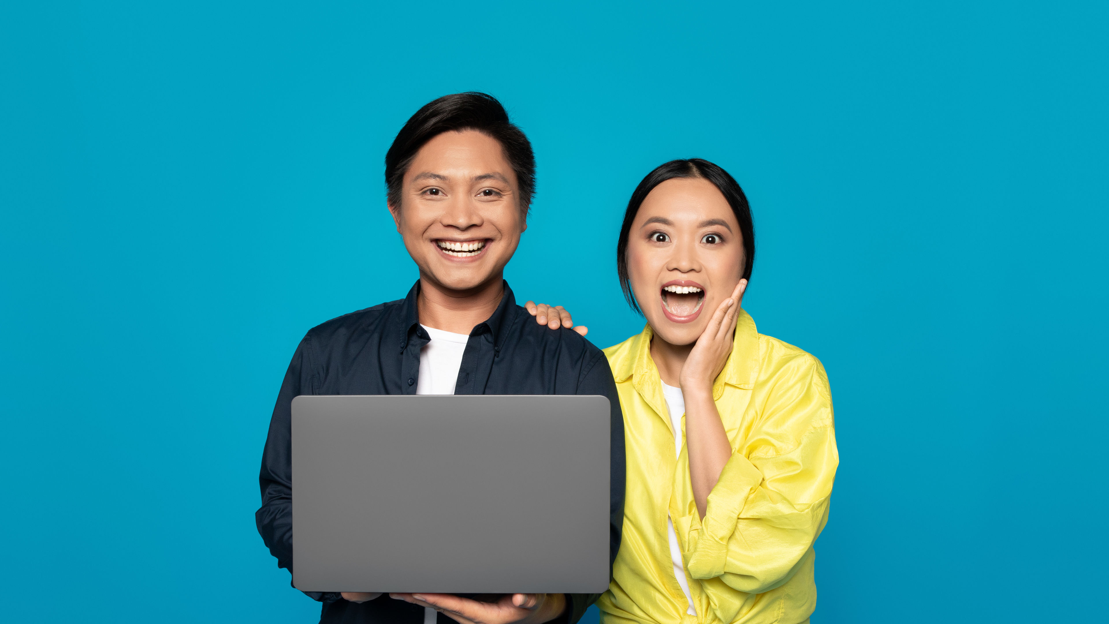 A happy couple with a silver laptop in hand 