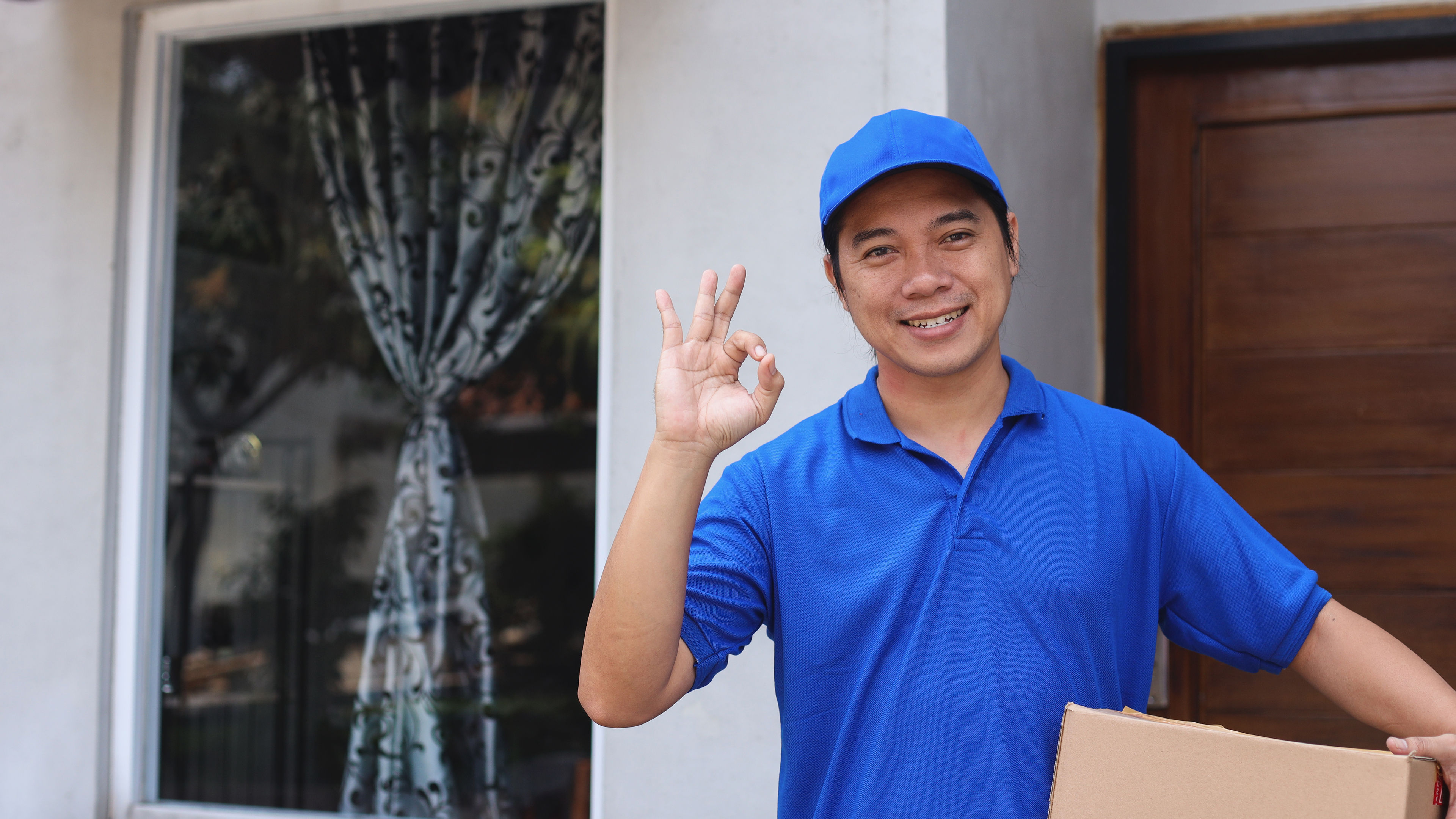 A happy delivery man with a big carton in hand 
