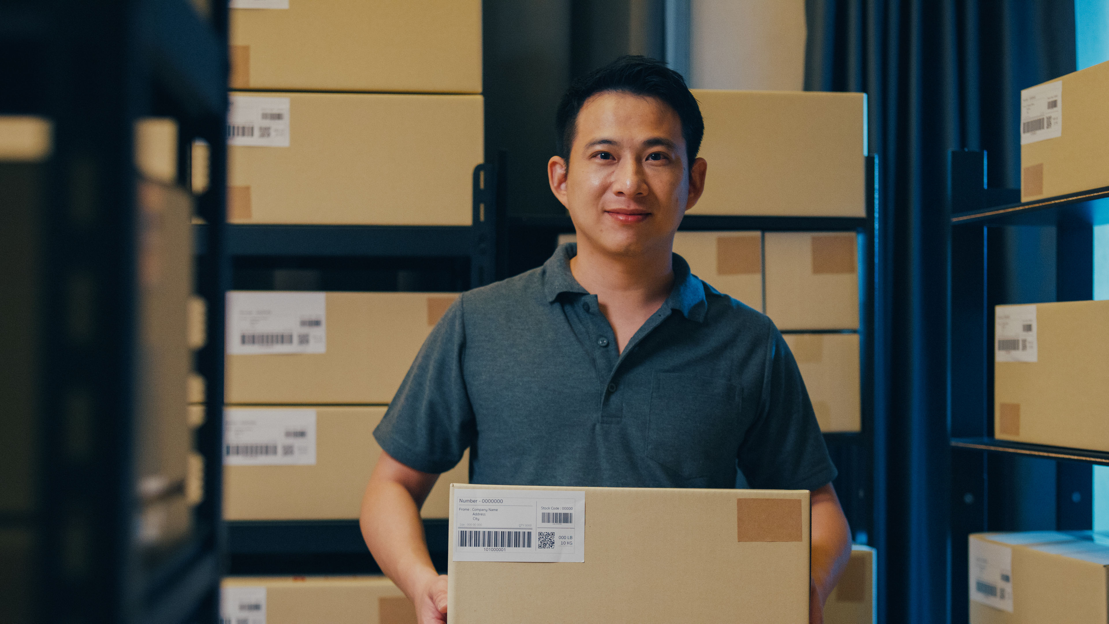 A man with a lot of carton behind and a carton in his hand 
