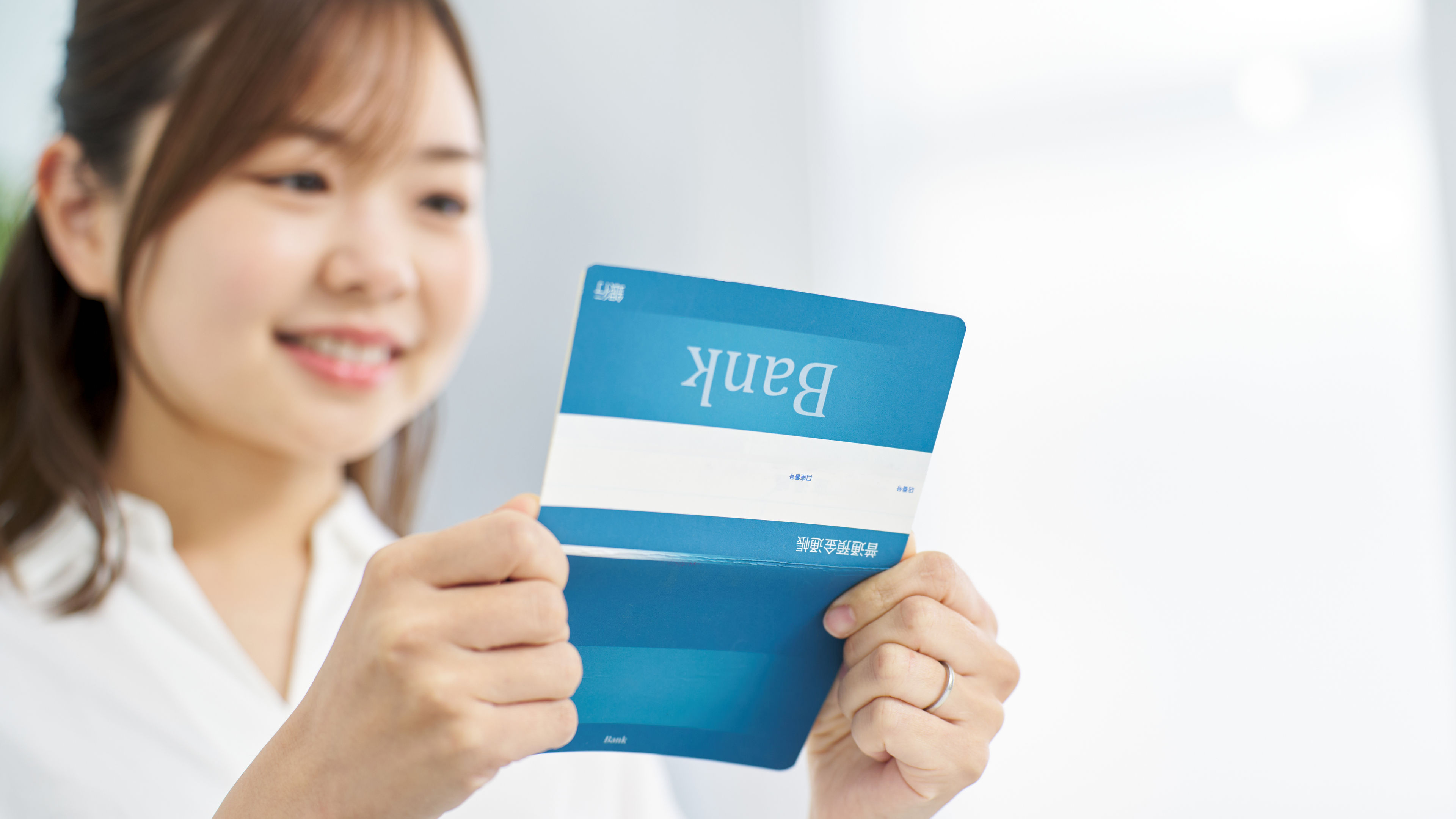 A woman looking at a bank passbook with a smile 