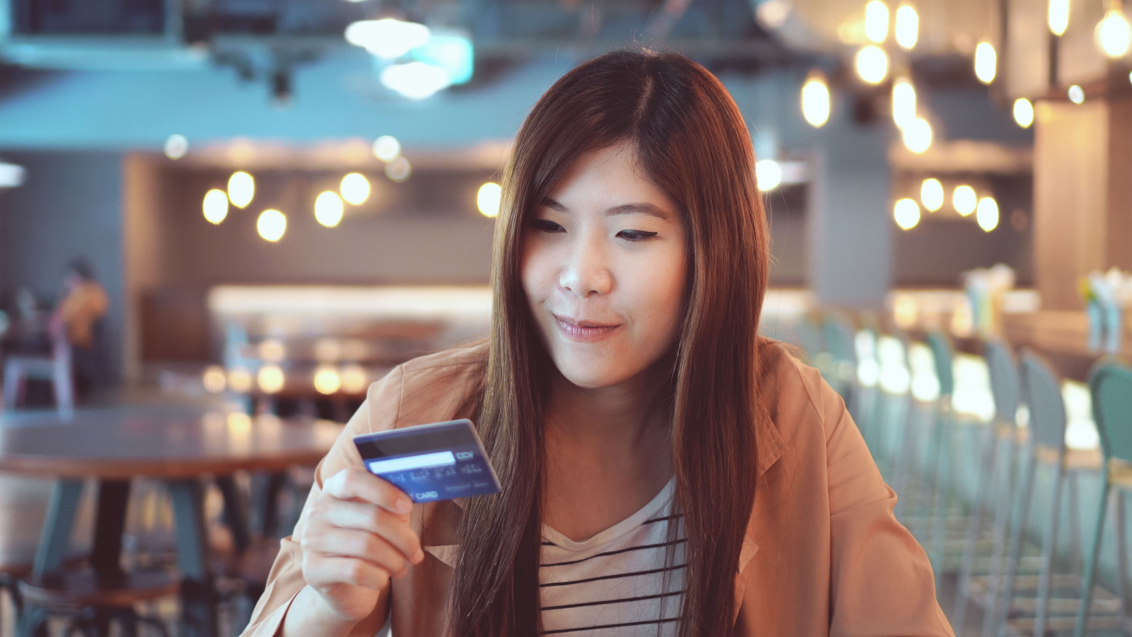 Asian businesswoman in casual suit using the credit card with computer for online shopping at co-working space, business technology and lifestyle concept 