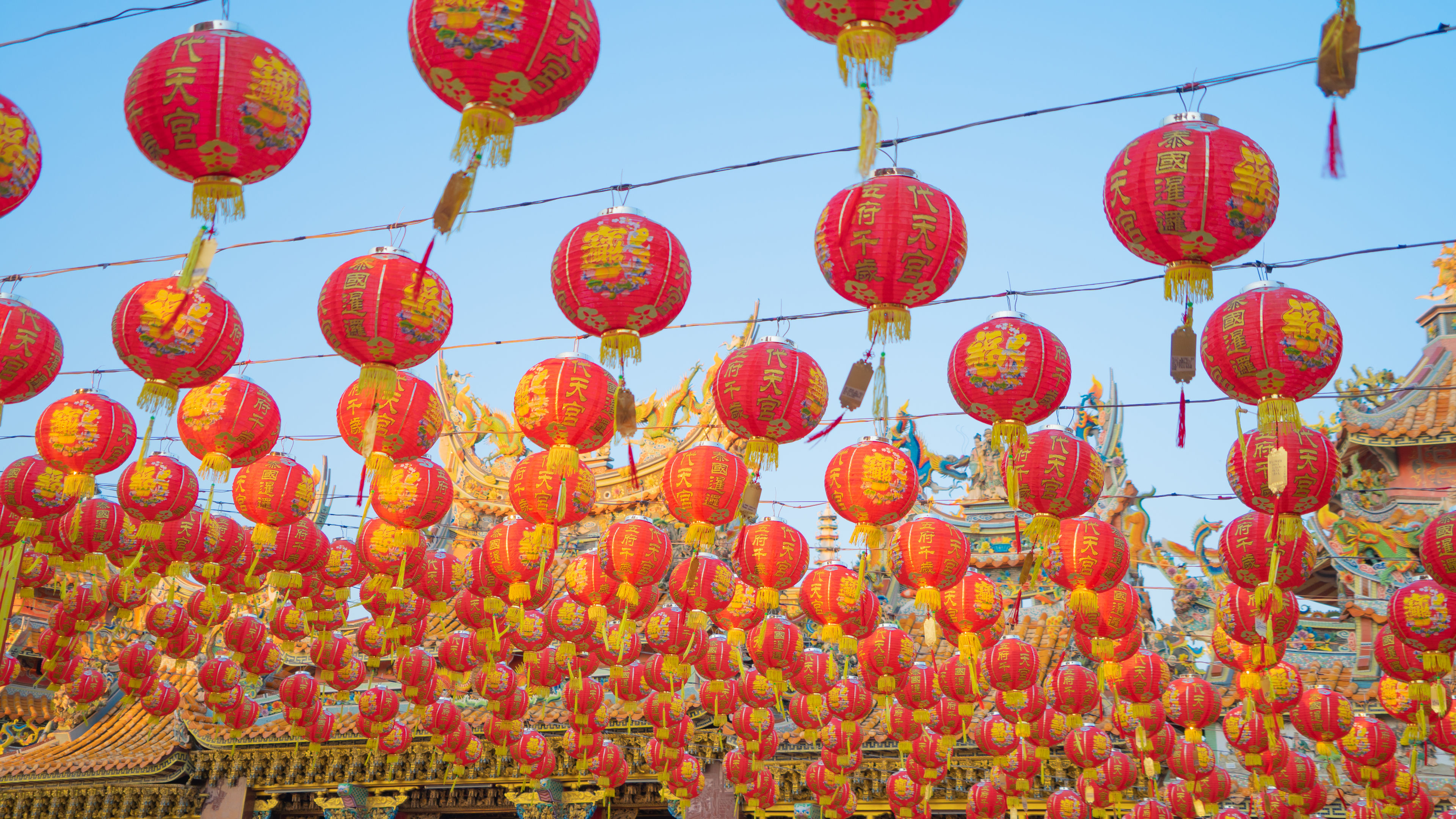 Traditional red Chinese lanterns hanging in rows under a clear blue sky 